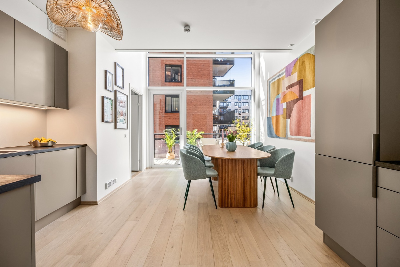 En sosial planløsning mot kjøkken med svært store vindusflater Galleribilde