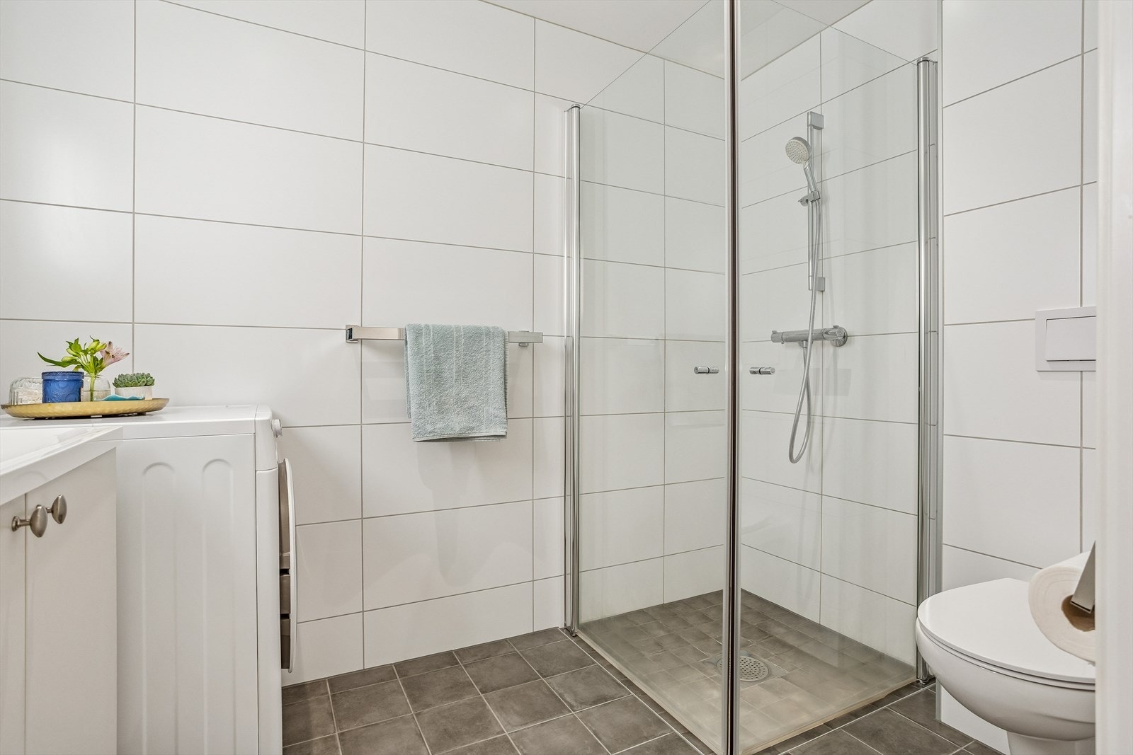 Badet er utstyrt med vegghengt toalett og dusjdører i klart glass. Galleribilde