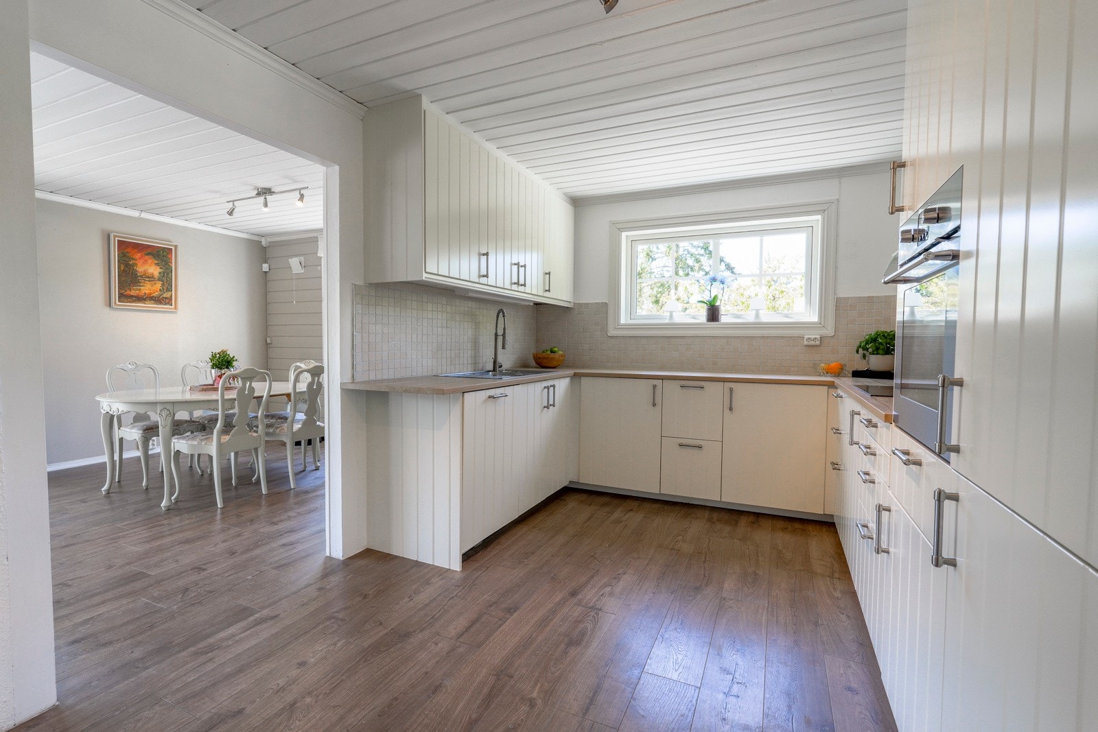 Hyggelig kjøkken med innredning med hvite profilerte fronter, laminat benkeplate med vask. Galleribilde