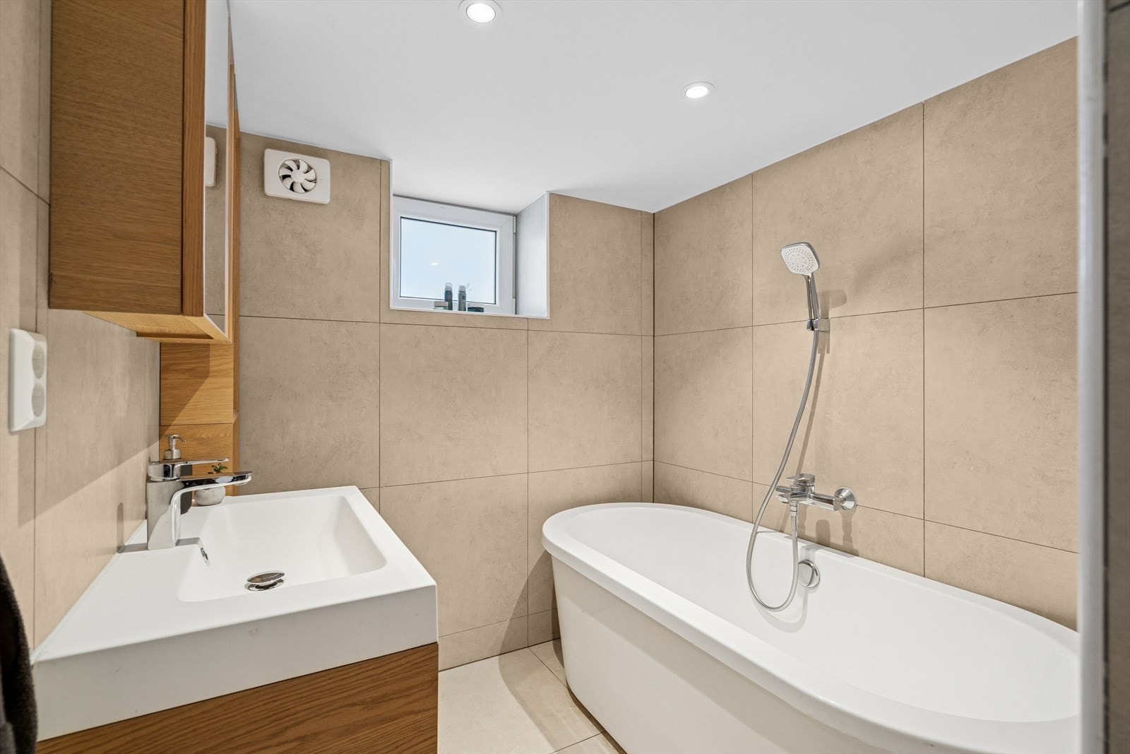 Lekkert og helfliset bad med badekar og pent servantskap. Galleribilde