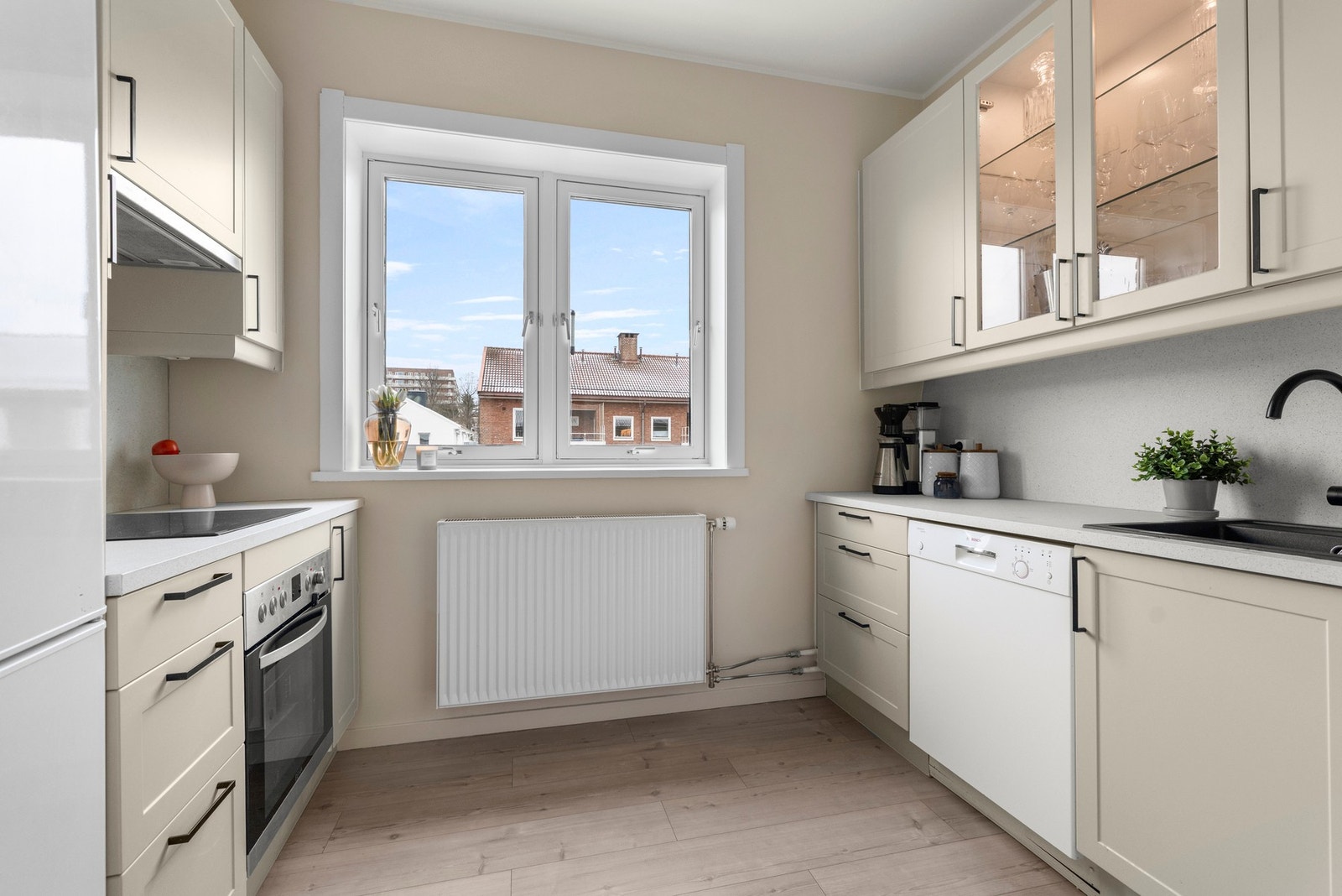 Pent og velholdt kjøkken fra IKEA med sorte håndtak, oppgradert i 2025 med nye fronter, benkeplater og integrerte hvitevarer. Galleribilde