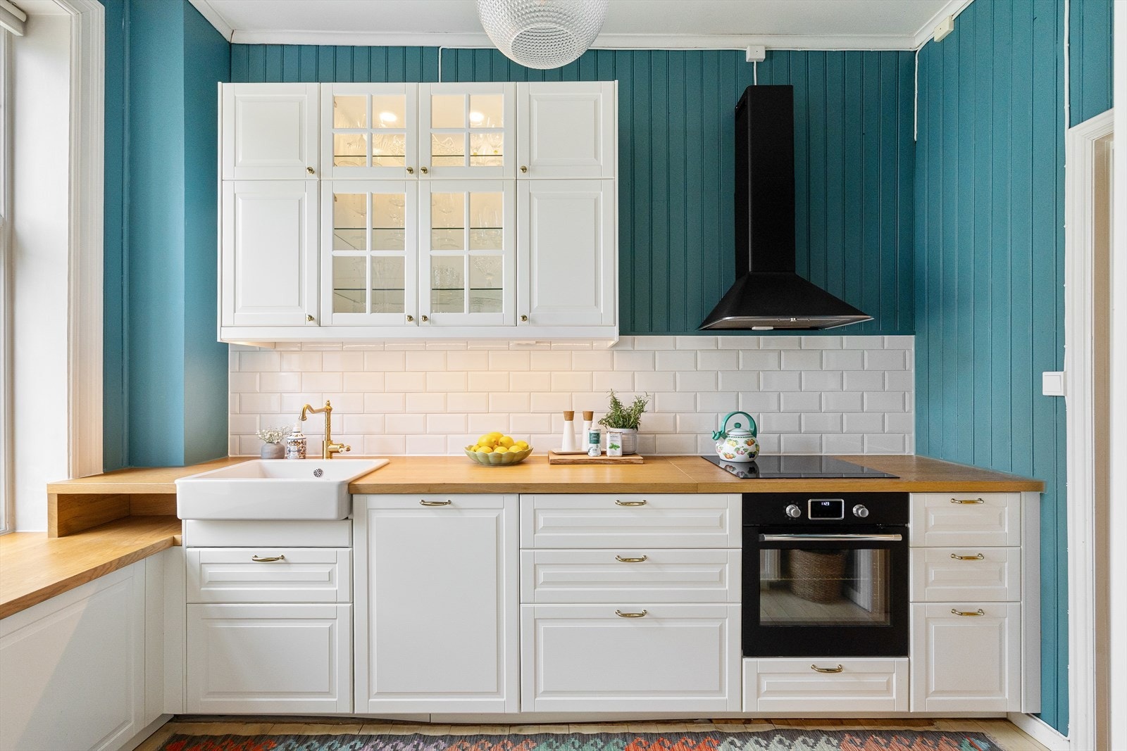 Benkeplaten er av finer dekket med massiv eik og nedfelt vaskekum i keramikk samt belysning over benkeplaten. Det er fliser mellom kjøkkenbenk og overskapene. Galleribilde