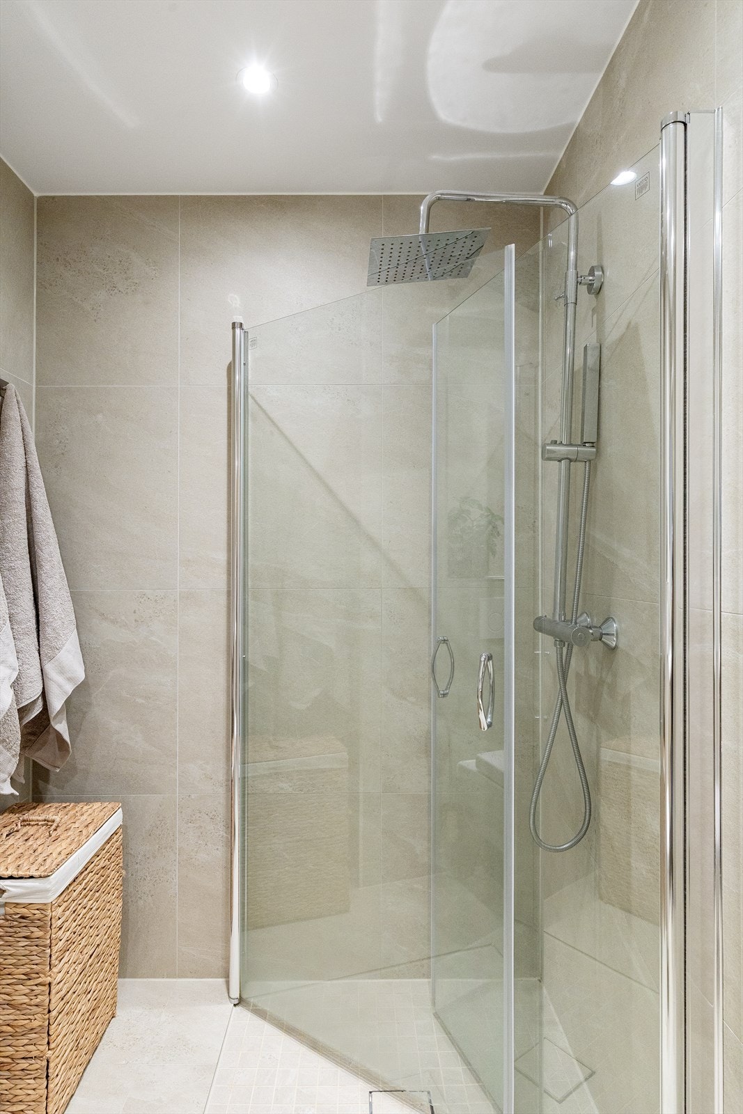 Badet har servantinnredning med overliggende servant, samt vegghengt speil og downlights. Det er dusjhjørne med glassdører og vegghengt toalett. Galleribilde