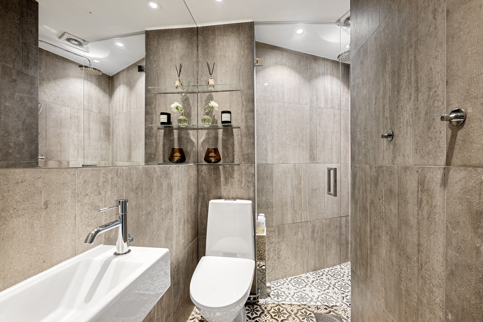 Delikat baderom med en klassisk og funksjonell utforming med dusj, servant og toalett. Galleribilde