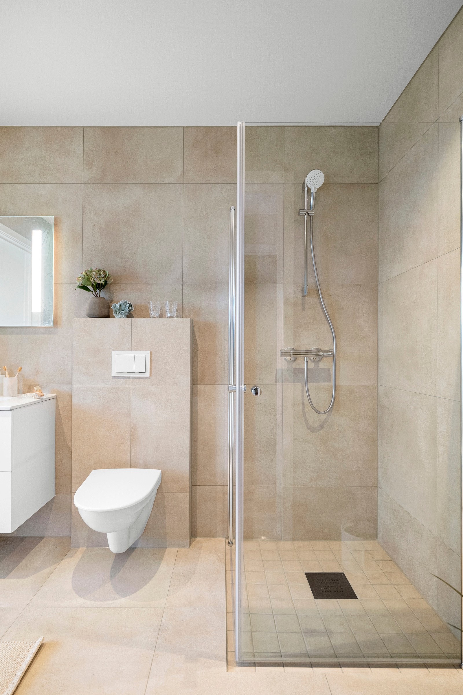 Helfliset bad med gulvvarme, vegghengt toalett og et dusjhjørne med innfellbare vegger. Galleribilde