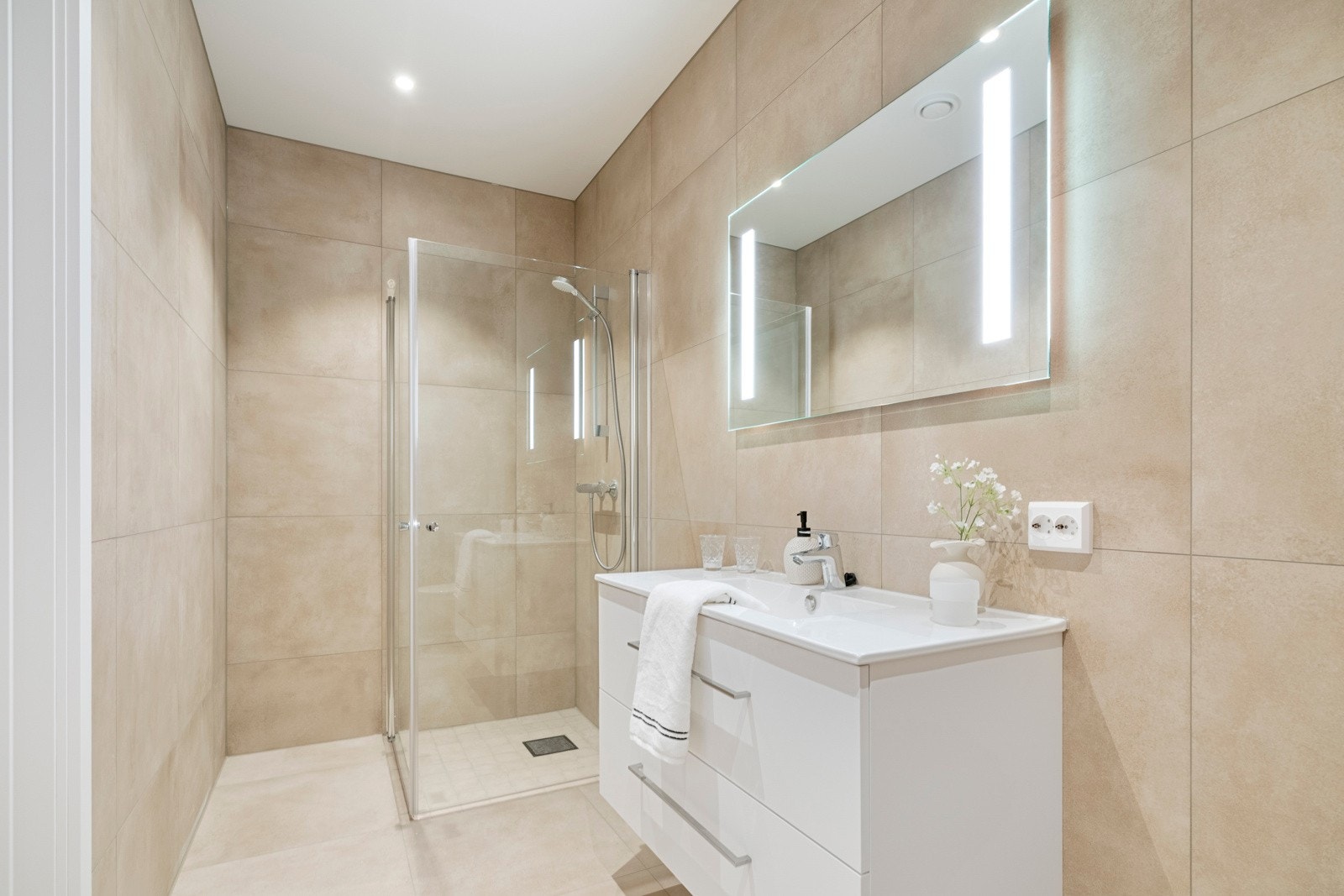 Badet i første etasje er helfliset med gulvvarme, vegghengt toalett og et dusjhjørne med innfellbare vegger. Galleribilde