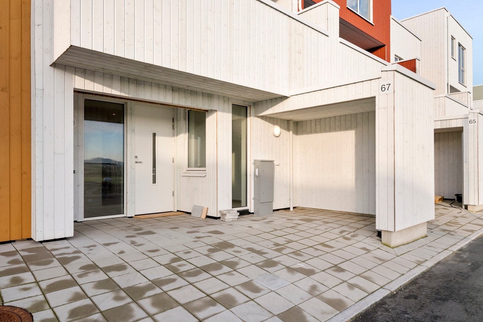 Rekkehuset har et overbygget inngangsparti med plass til benker eller kafésett. Galleribilde