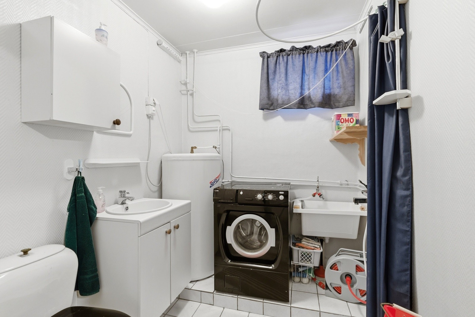 Vaskerom med flislagt gulv. Innredning med nedfelt servant, toalett og opplegg for vaskemaskin. Galleribilde