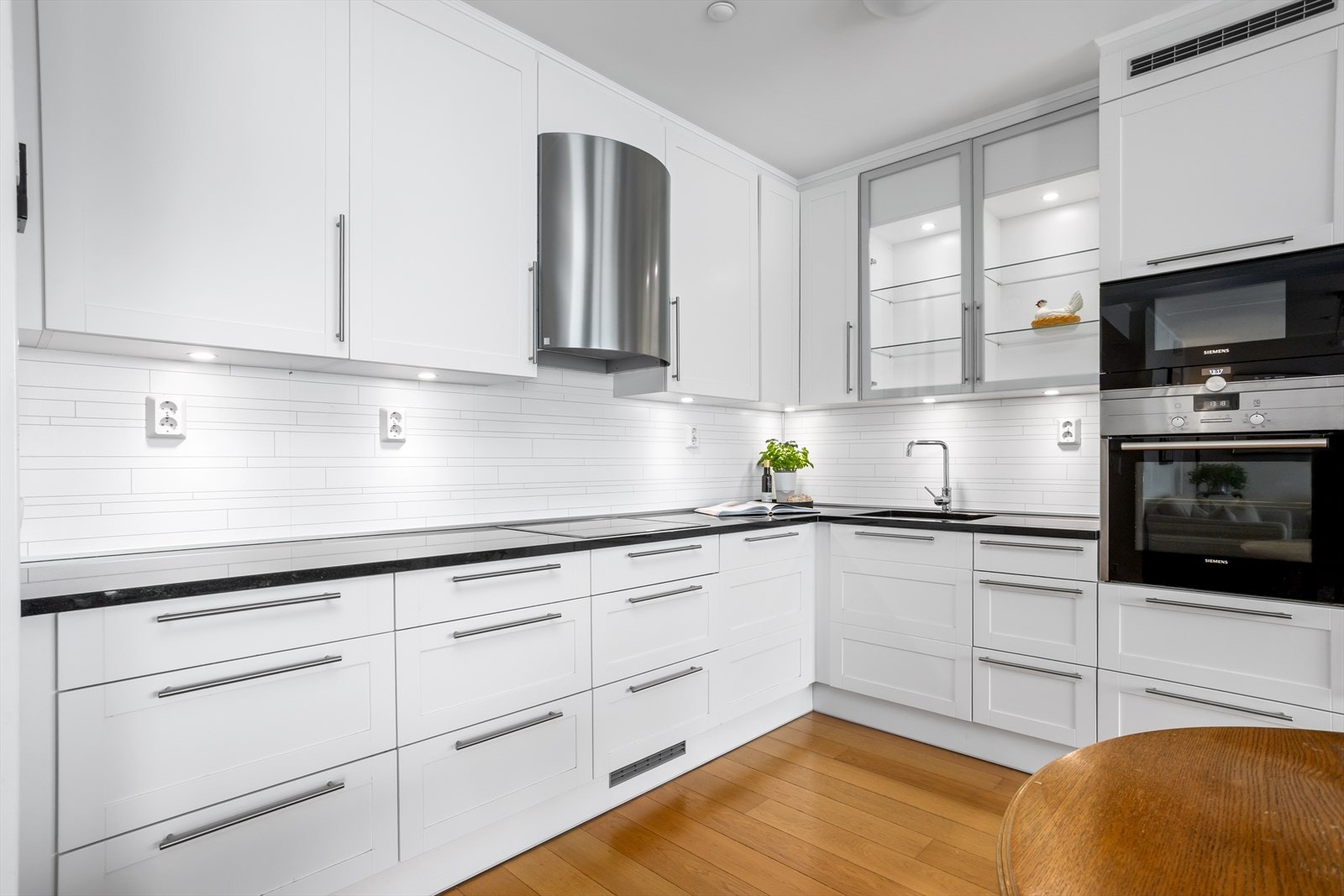 Innholdsrikt kjøkken med bl.a. benkeplater av stein og integrerte hvitevarer Galleribilde