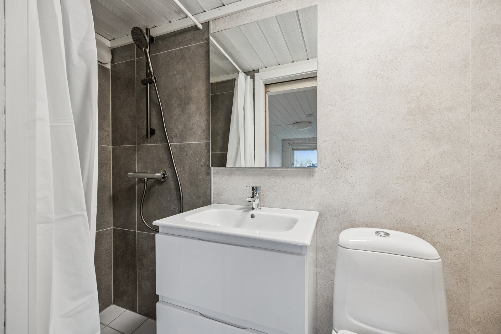 Bad med dusj, servant, toalett og vaskemaskin. Galleribilde