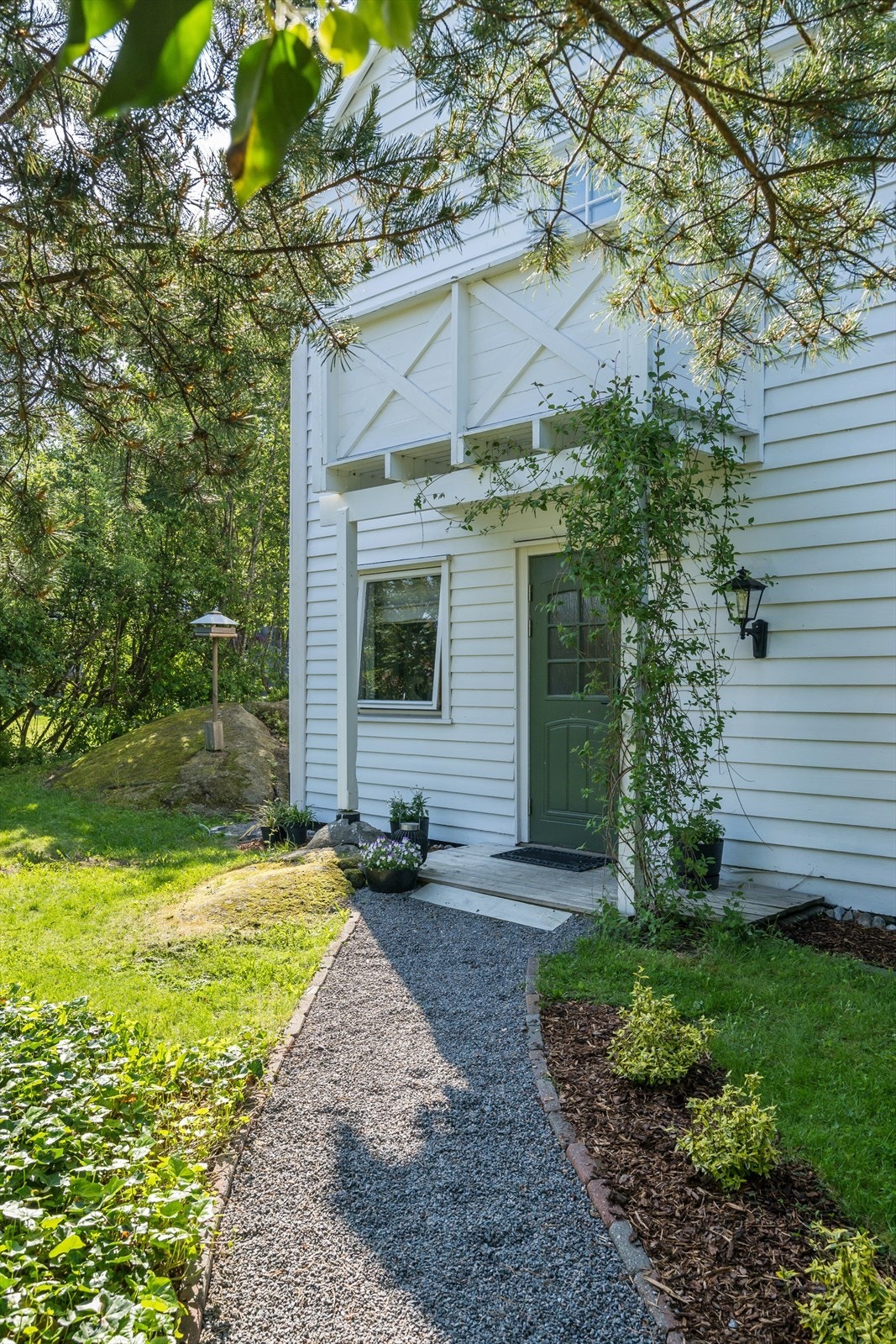 Pent overbygget inngangsparti med opparbeidet sti og bed. Galleribilde