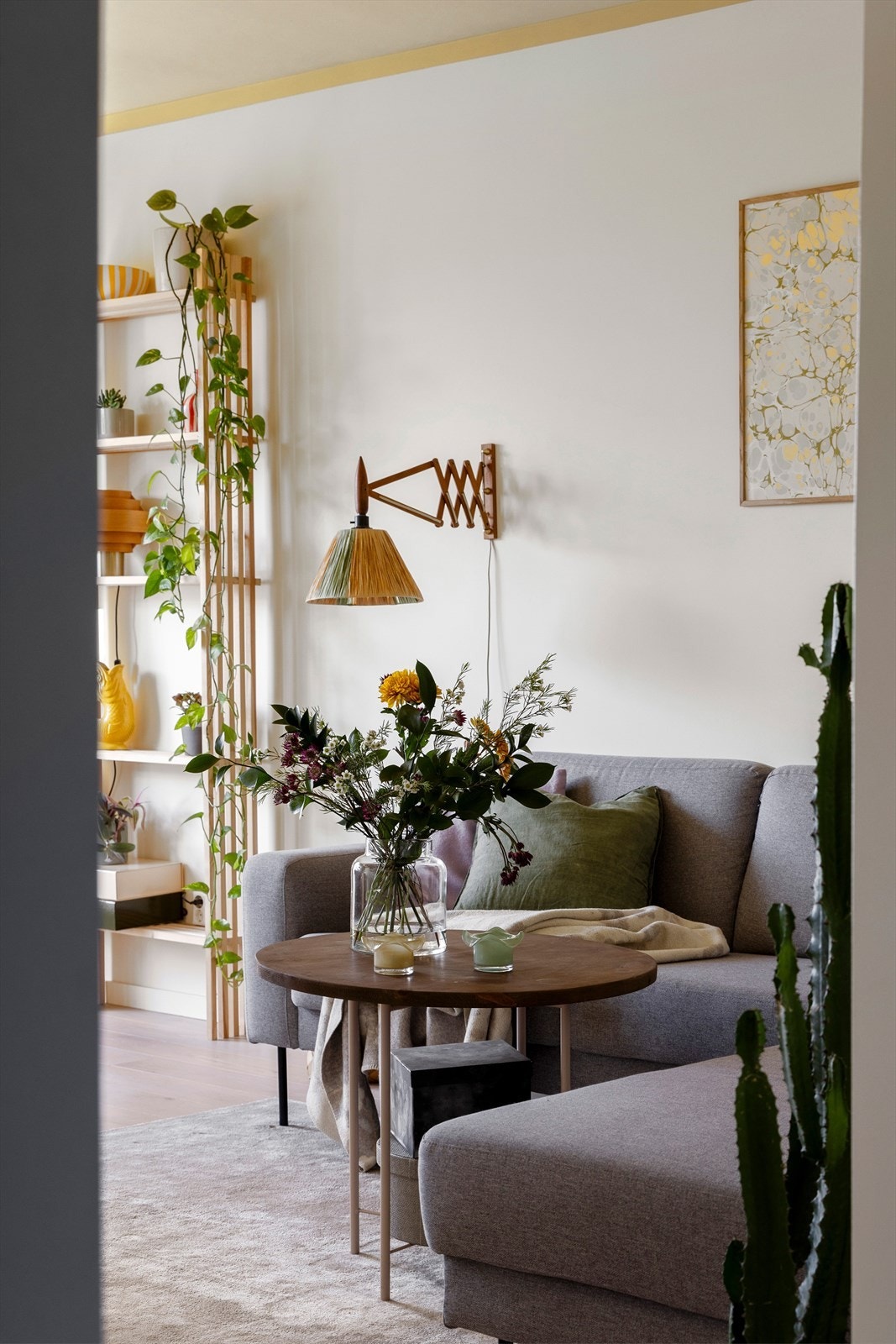 Hyggelig stue med naturlig møbleringssone for sofagruppe og salongbord - fine detaljer, grønne innslag og god flyt videre inn mot spiseplassen ved vinduet. Galleribilde