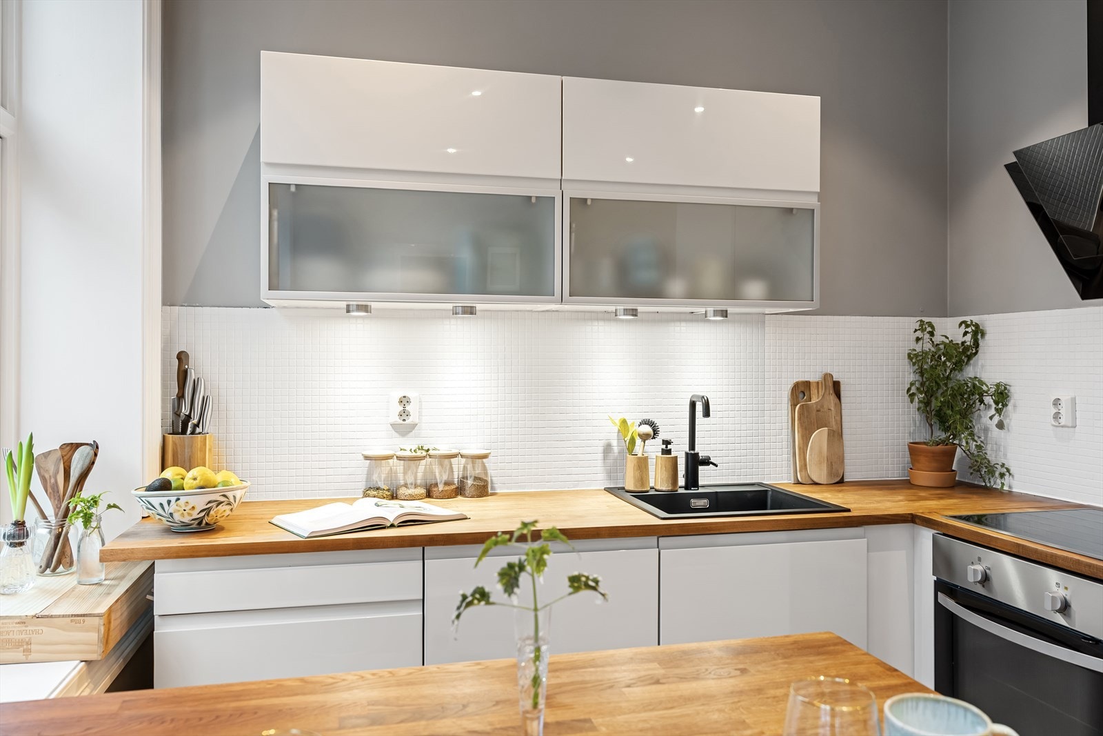 Innredningen består av både over- og underskap, lys under overskap. Fliser mellom benkeplate og overskap. Galleribilde