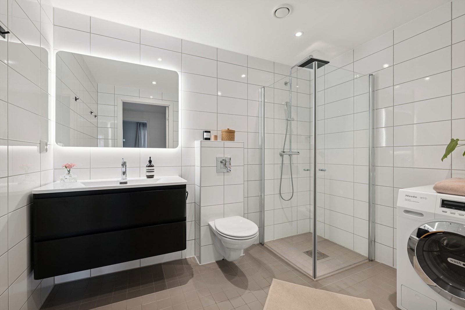 Flislagt bad med vegghengt toalett og opplegg for vaskemaskin Galleribilde