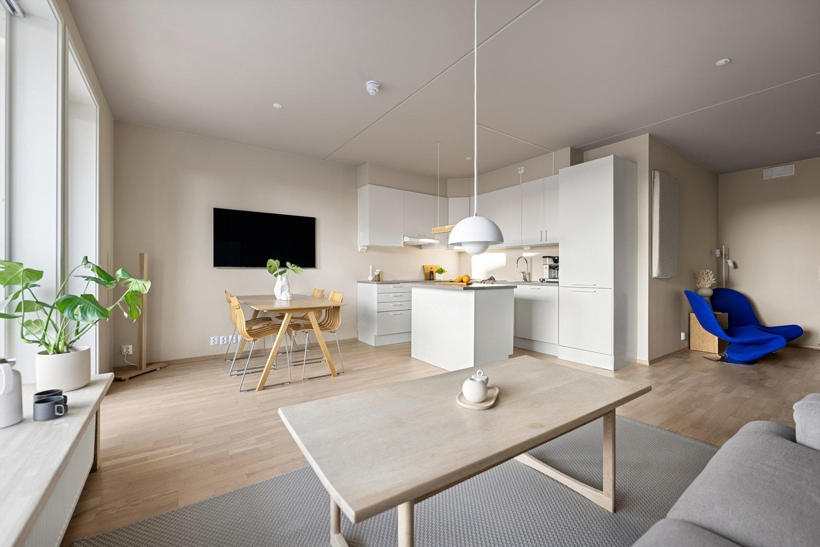 Stue/kjøkken en en åpen løsning hvor kjøkkenet blir naturlig adskilt med en kjøkkenøy Galleribilde