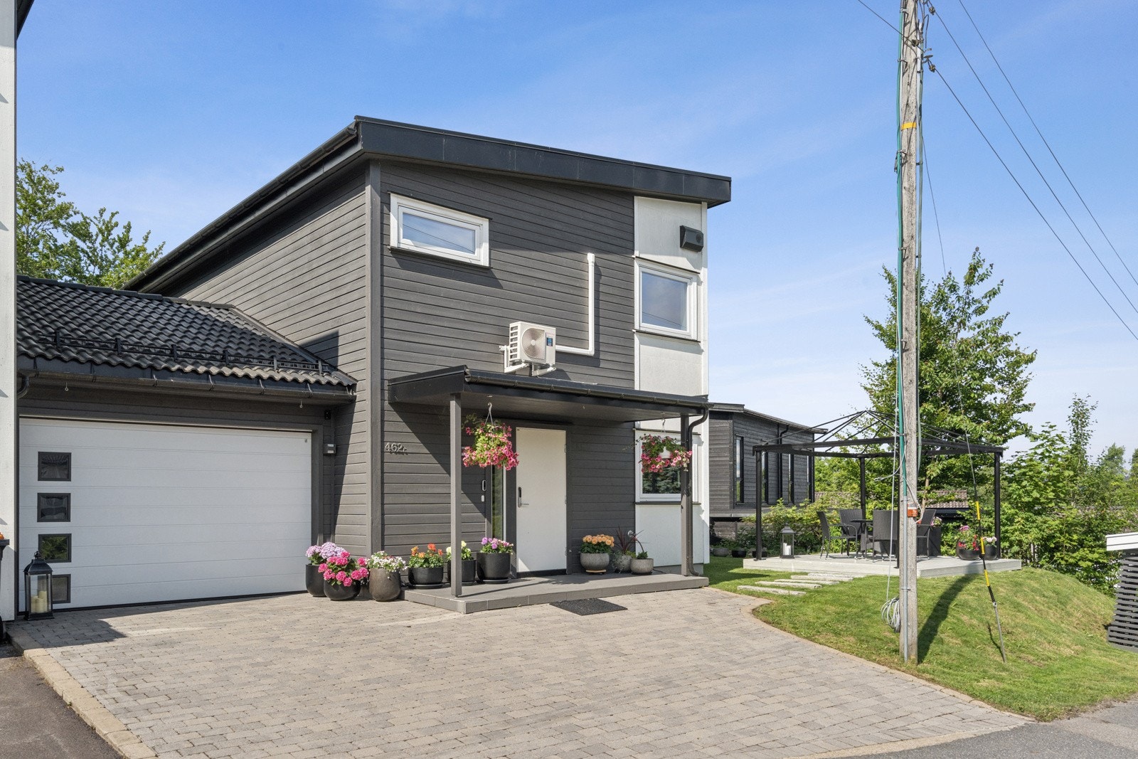 Parkering i garasje med motorisert port med glassdesign-vinduer fra Alutech, samt i gårdsrommet med belegningsstein. Garasjen er malt med utvendig maling, to strøk for god beskyttelse og er innredet med hyller og sykkelstativ. Galleribilde