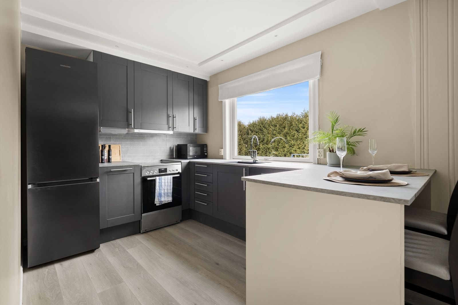 Pent kjøkken med praktisk innredning og god skap- og benkeplass. Oppvaskmaskin, kjøleskap, komfyr og vaskemaskin medfølger. Galleribilde