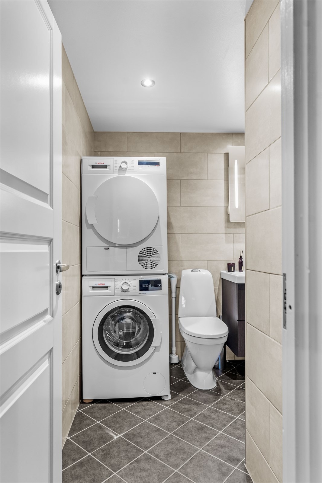 Delikat og flislagt baderom med opplegg for vaskemaskin og tørketrommel. Galleribilde
