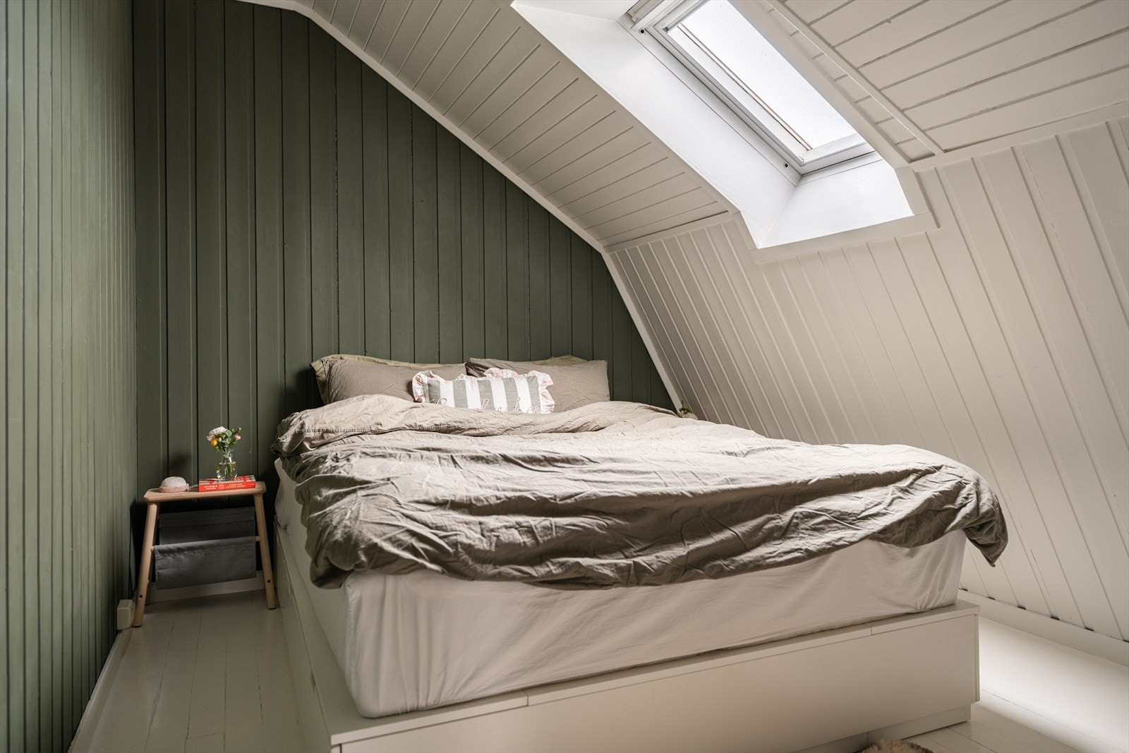 Rommet har malte tregulv og et takvindu med blendingsgardin. Galleribilde