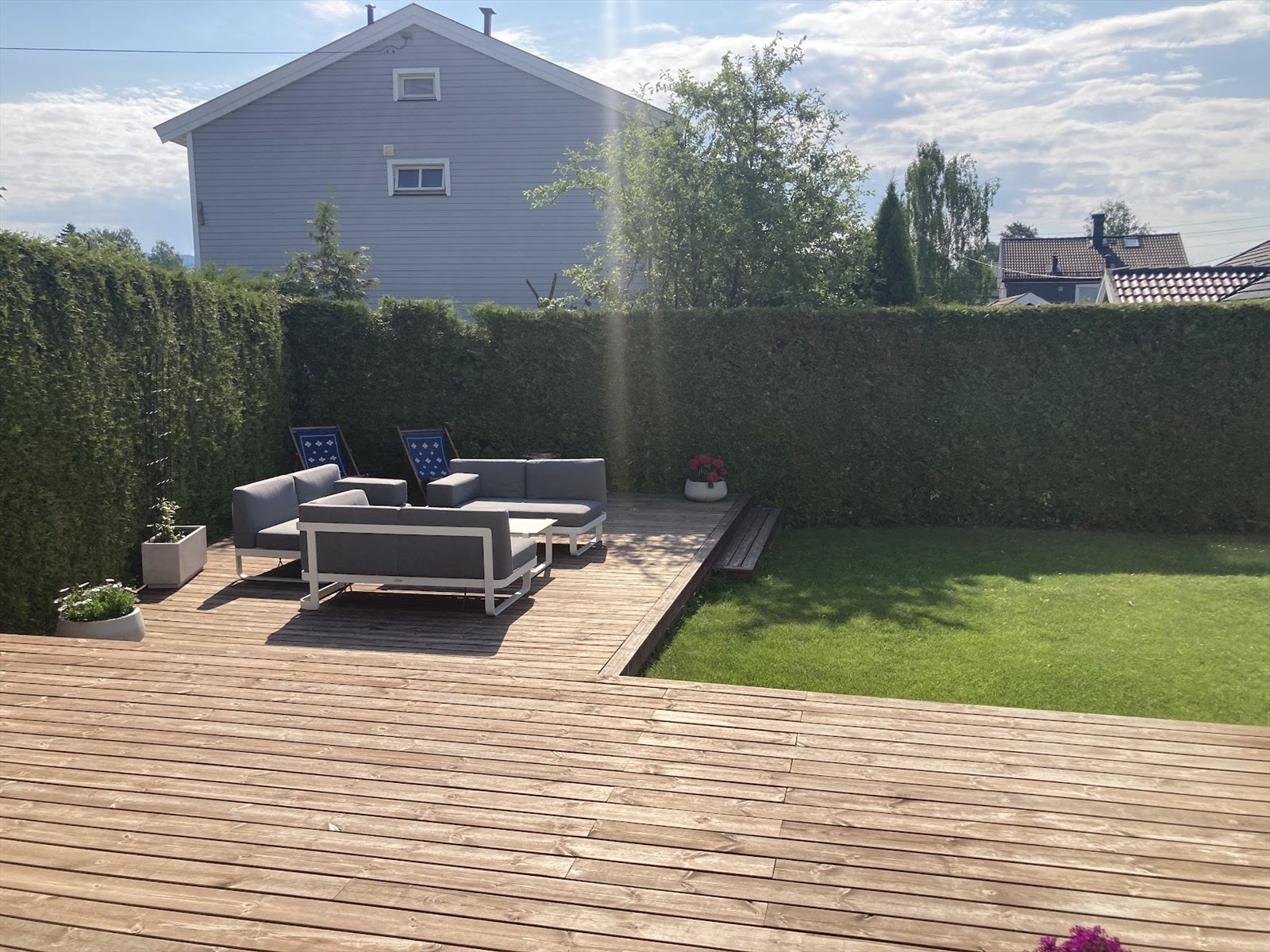 Selgers sommerbilde. Den sørvendte terrassen på 85 m² ble anlagt i 2021 og har trapp ned til hagen. Galleribilde