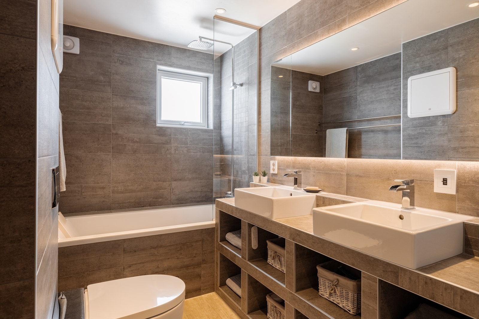 Badet har en plassbygget, flislagt servantløsning med hyller og to toppmonterte servanter. Galleribilde