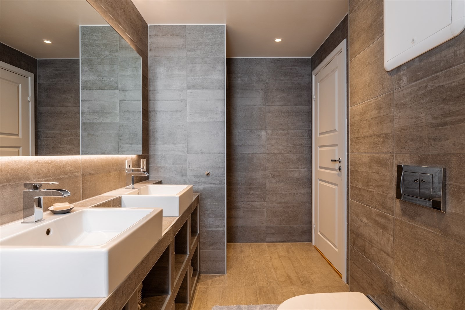 Her er det varmekabler i gulvet, downlights i taket og et veggmontert toalett med spylefunksjon. Galleribilde