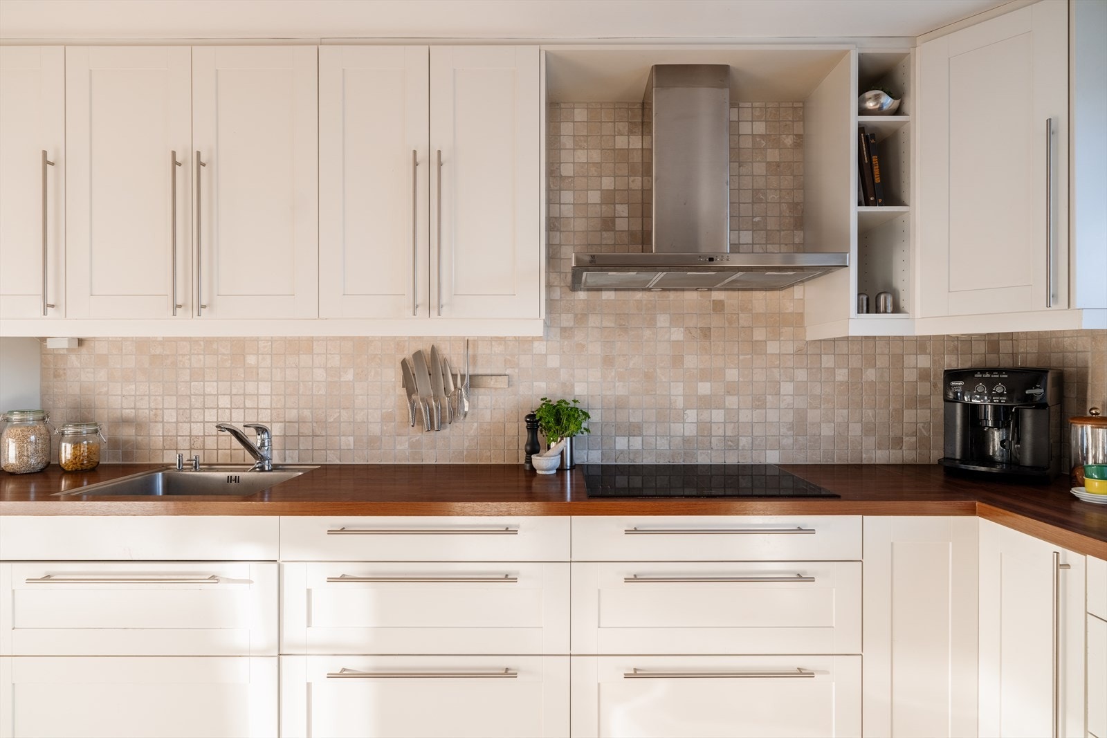 Laminatbenkeplate med planlimt kum i rustfritt stål og flislagt vegg over benken. Galleribilde