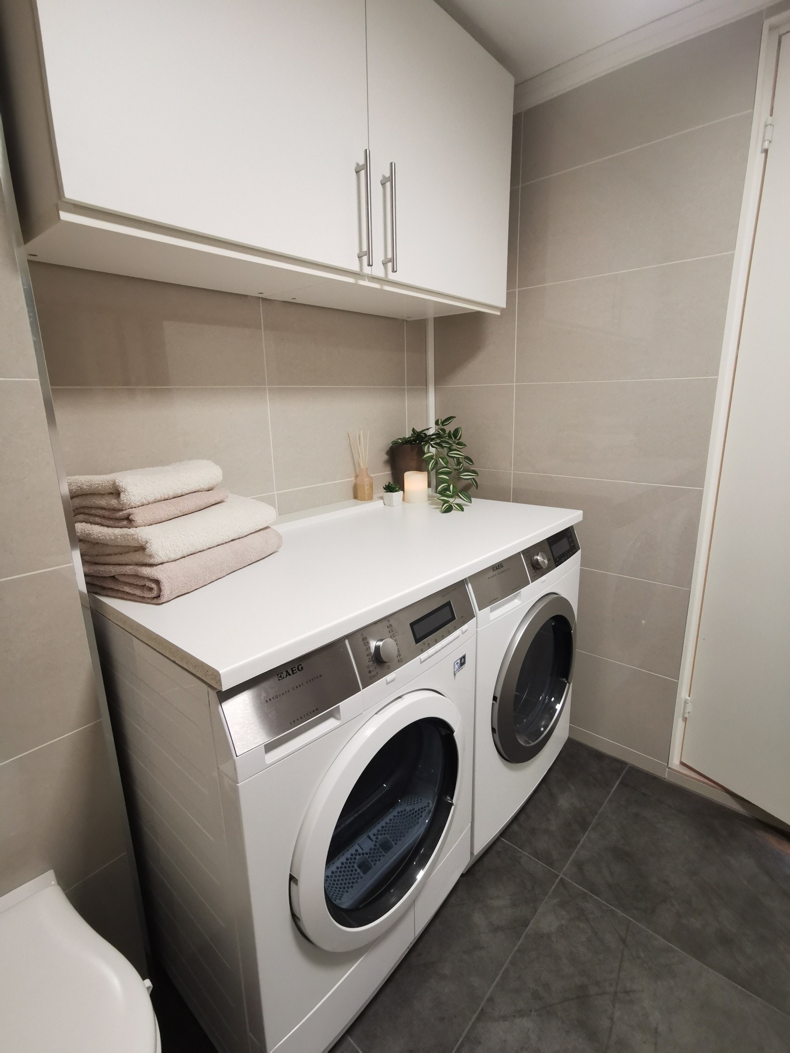 Baderomsinnredning bestående av benkeskap med glatte fronter, servant og veggskap med speilfronter over servant, dusj med innfellbare dører i herdet glass og veggfestet klosett med innebygget sisterne. Galleribilde