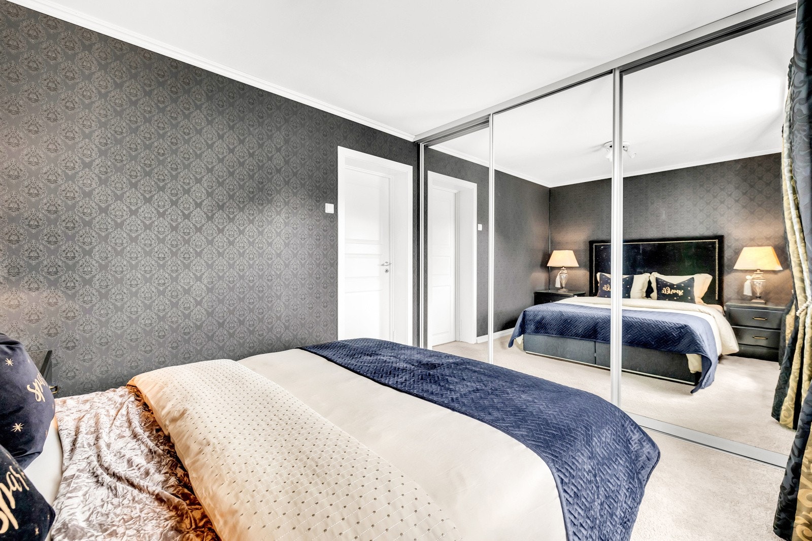 Rommet byr på god plass til dobbeltseng og nattbord, og har en praktisk skyvedørsgarderobe med speilfronter som både gir smart oppbevaring og bidrar til å åpne opp rommet visuelt. Galleribilde