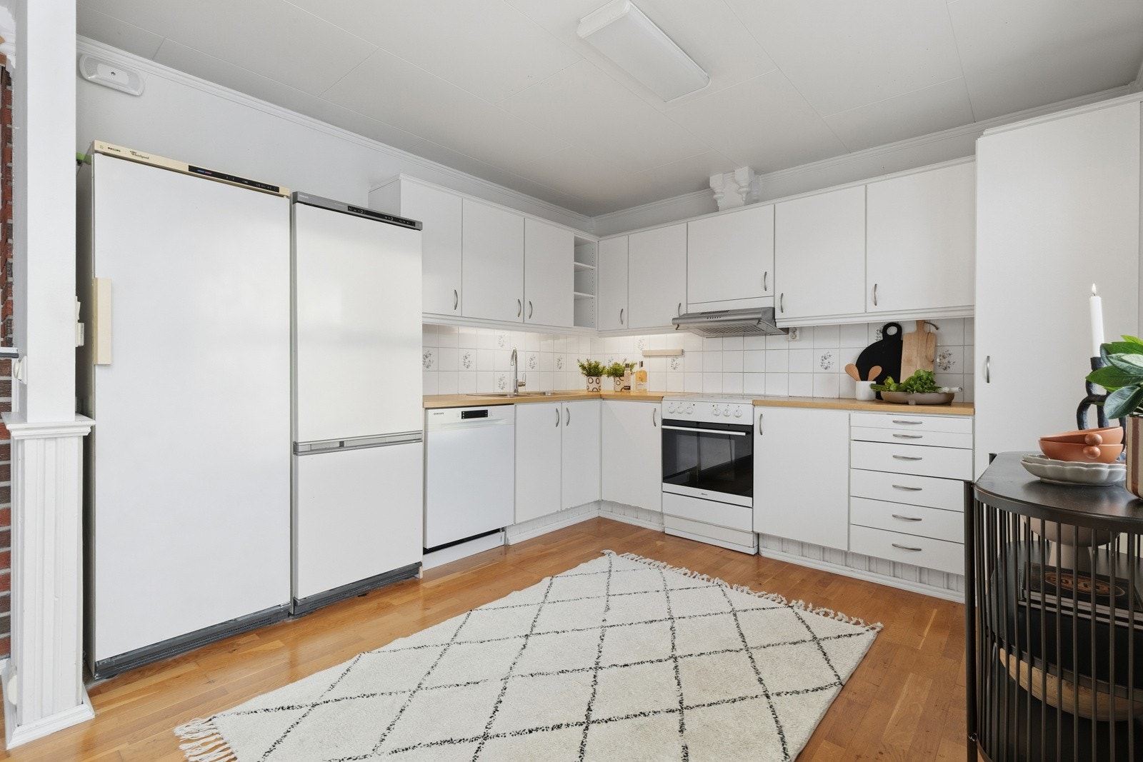 Kjøkkenet er innredet med klassisk kjøkkeninnredning med glatte fronter, laminert benkeplate og flis over benk. Galleribilde