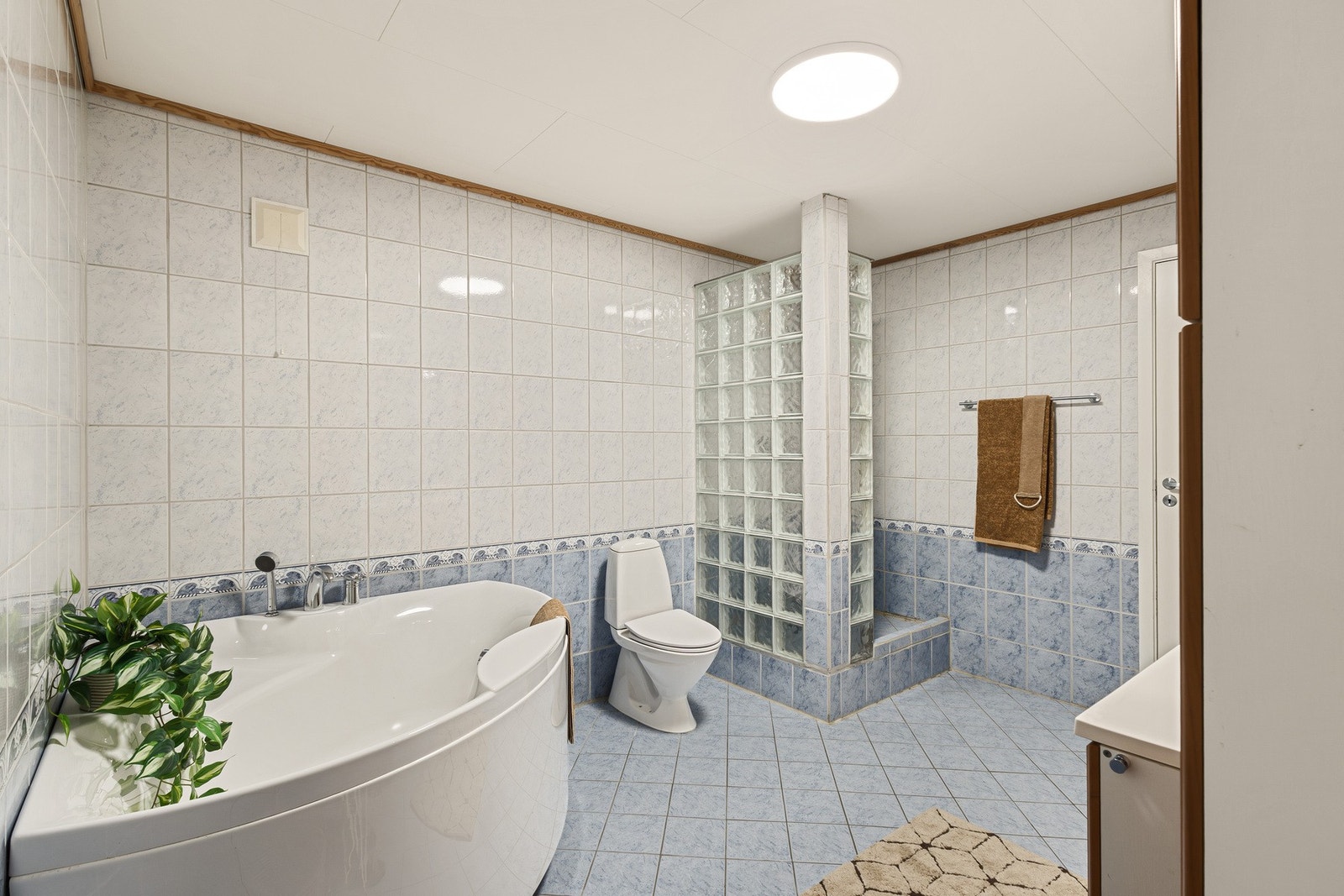 Inneholder innredning med nedfelt servant, dusjhjørne med glassbyggerstein, badekar og toalett Galleribilde