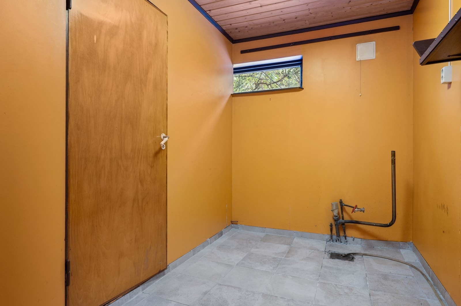 Praktisk vaskekjeller i underetasjen med flislagt gulv og opplegg for vaskemaskin. Galleribilde