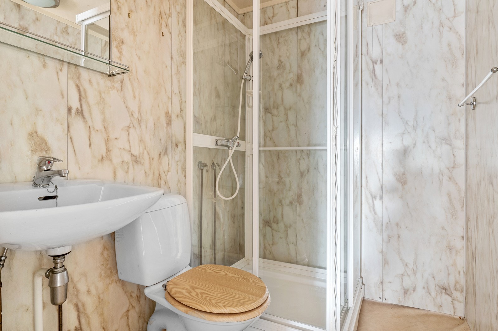 Badet i hybelen underetasjen er av eldre dato med belegg med oppbrett langs veggene på gulvet, og vårtromsplater på veggene. Det er utstyrt med WC, servant og dusjkabinett. Galleribilde