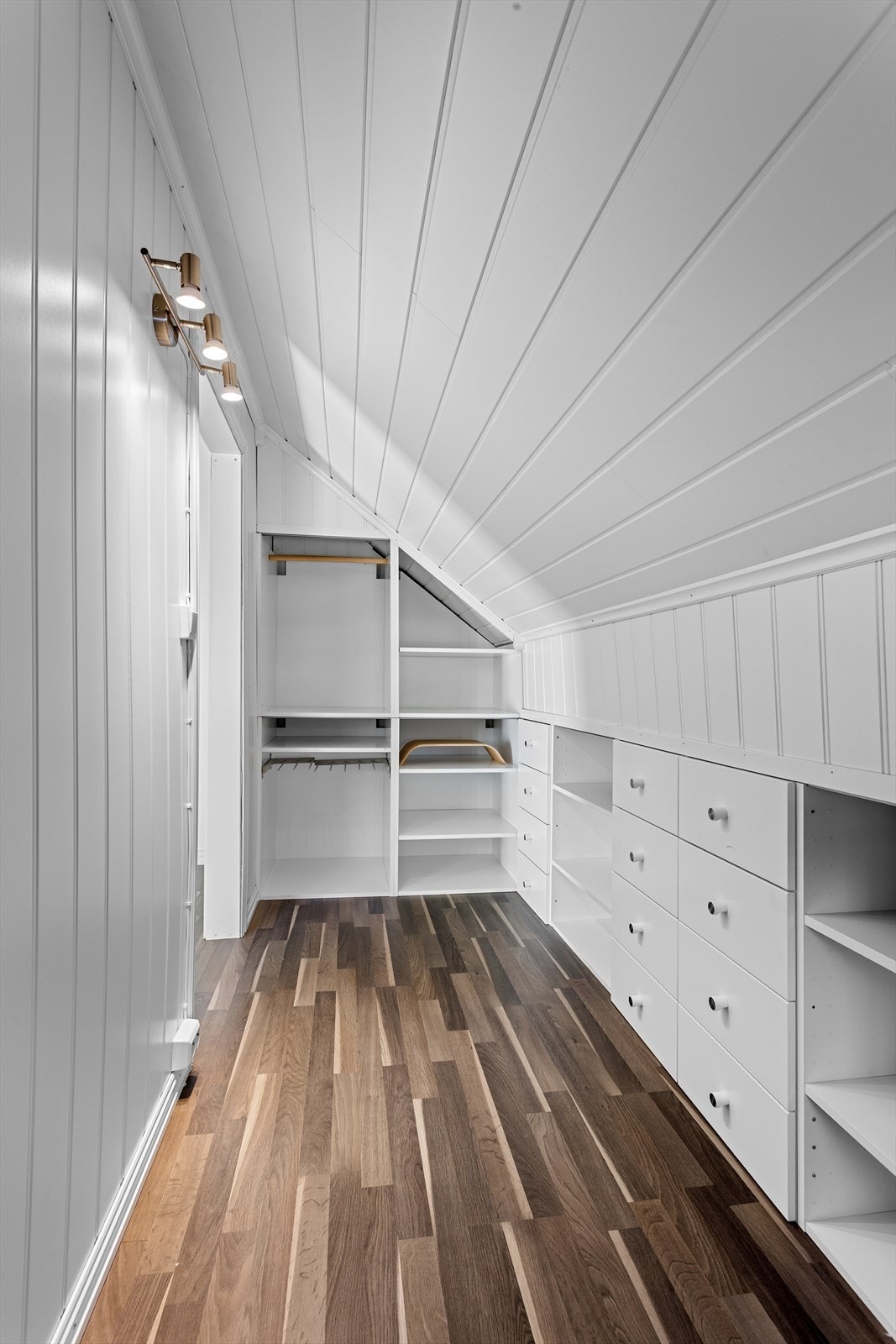 Innebygget garderobeløsning med klesskinner, hyller og skuffer i vegg Galleribilde