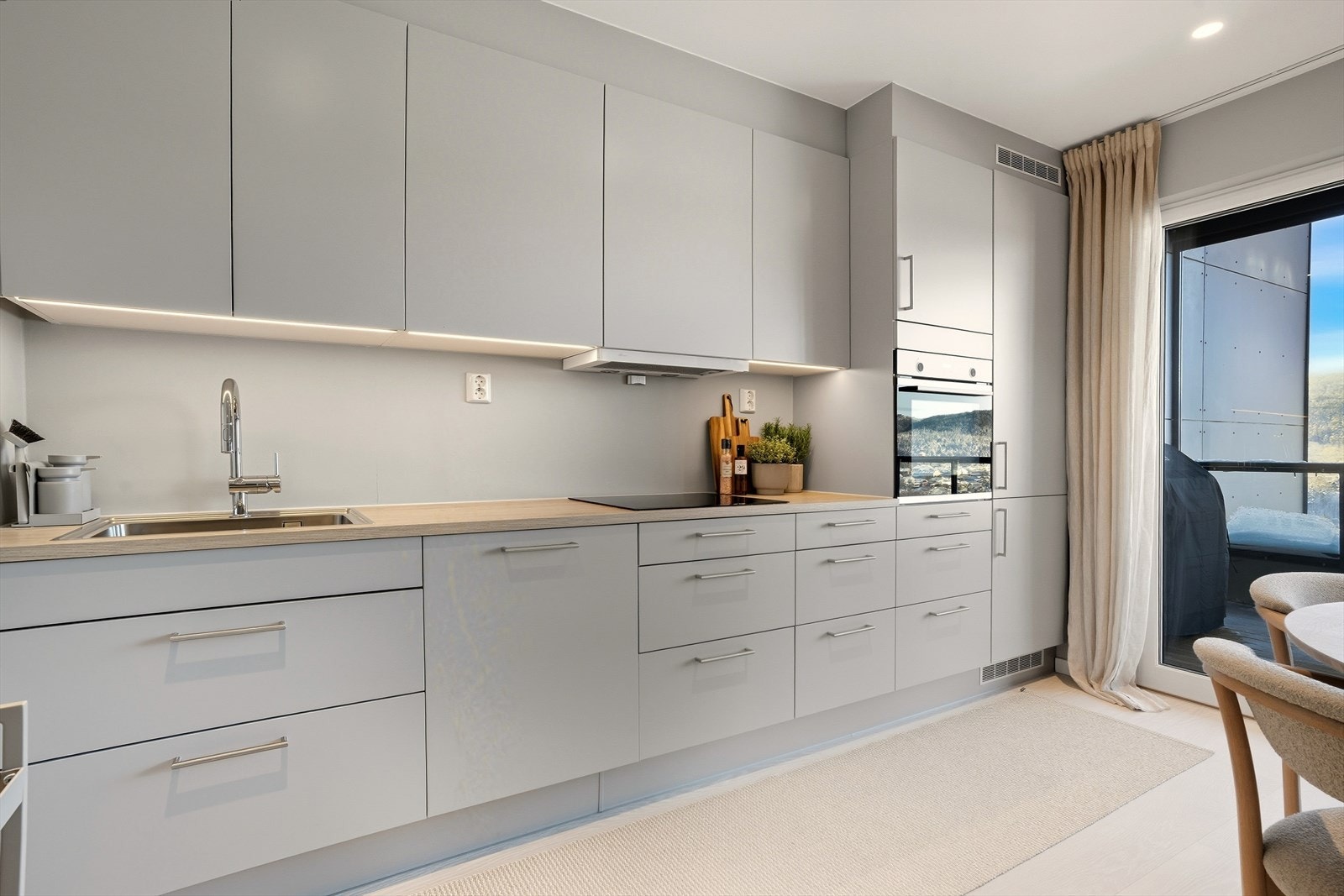 Kjøkkeninnredningen har slette, grå fronter og laminert benkeplate. Galleribilde