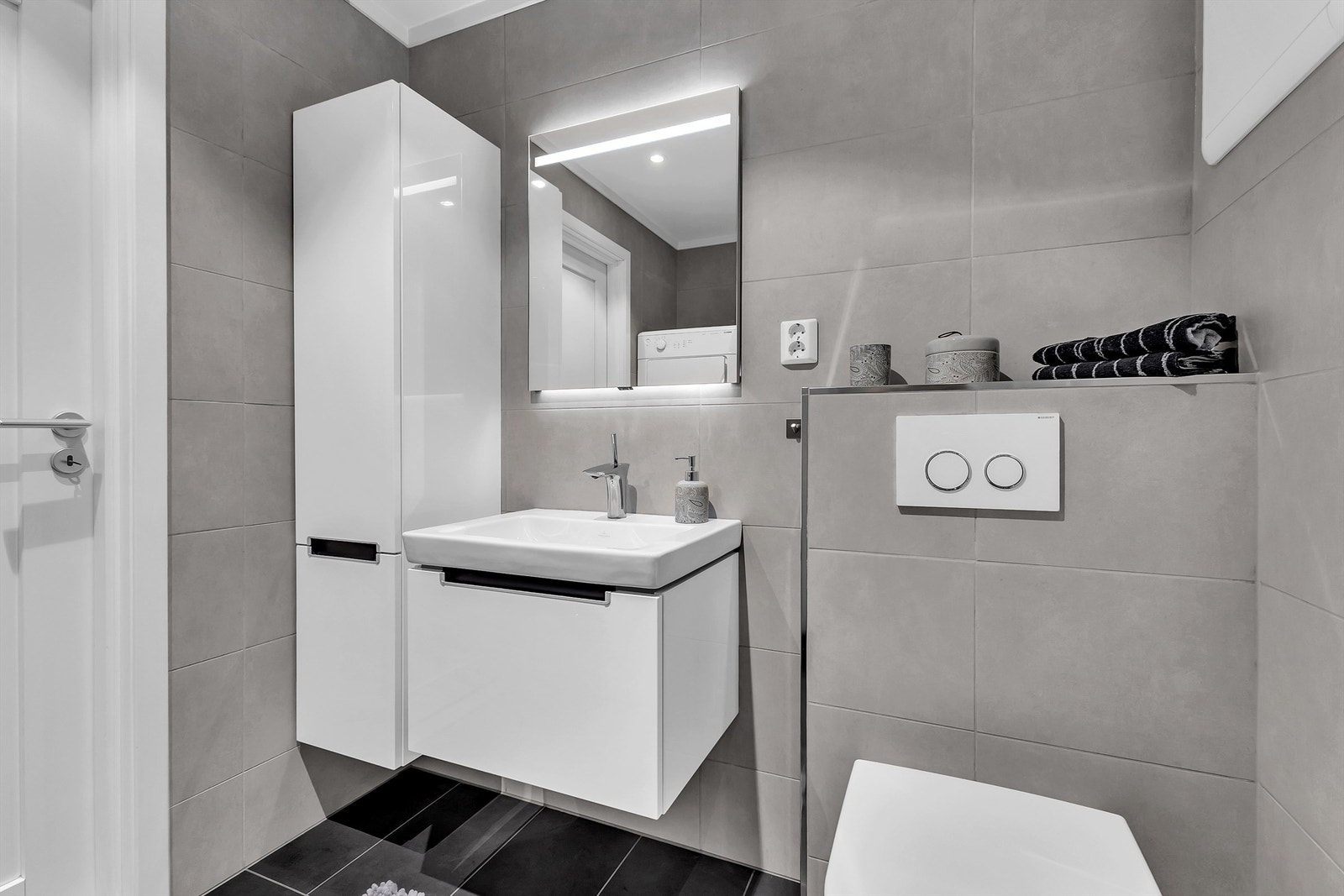 Badets moderne møbler har lett tilgjengelig oppbevaringsplass for håndklær og personlige effekter. Galleribilde