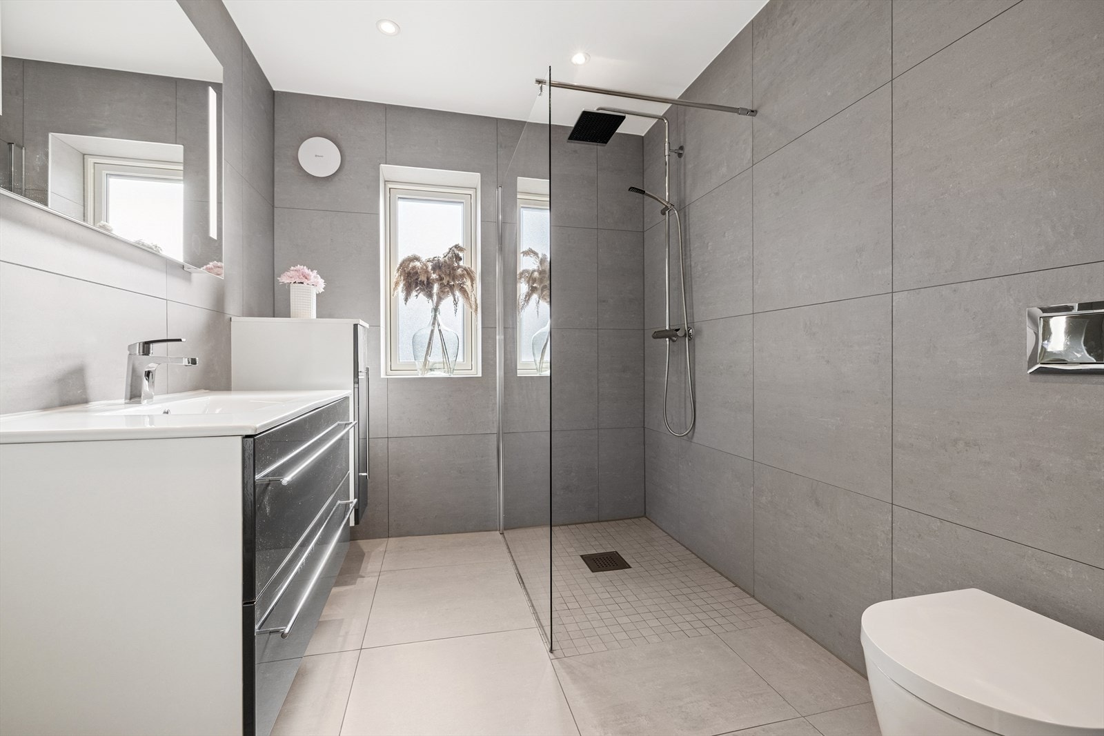 Bad nr 2 i denne etasjen har fliser på vegger og gulv med gulvvarme. Badet har innredning med nedfelt servant, veggmontert toalett og dusjhjørne. Galleribilde