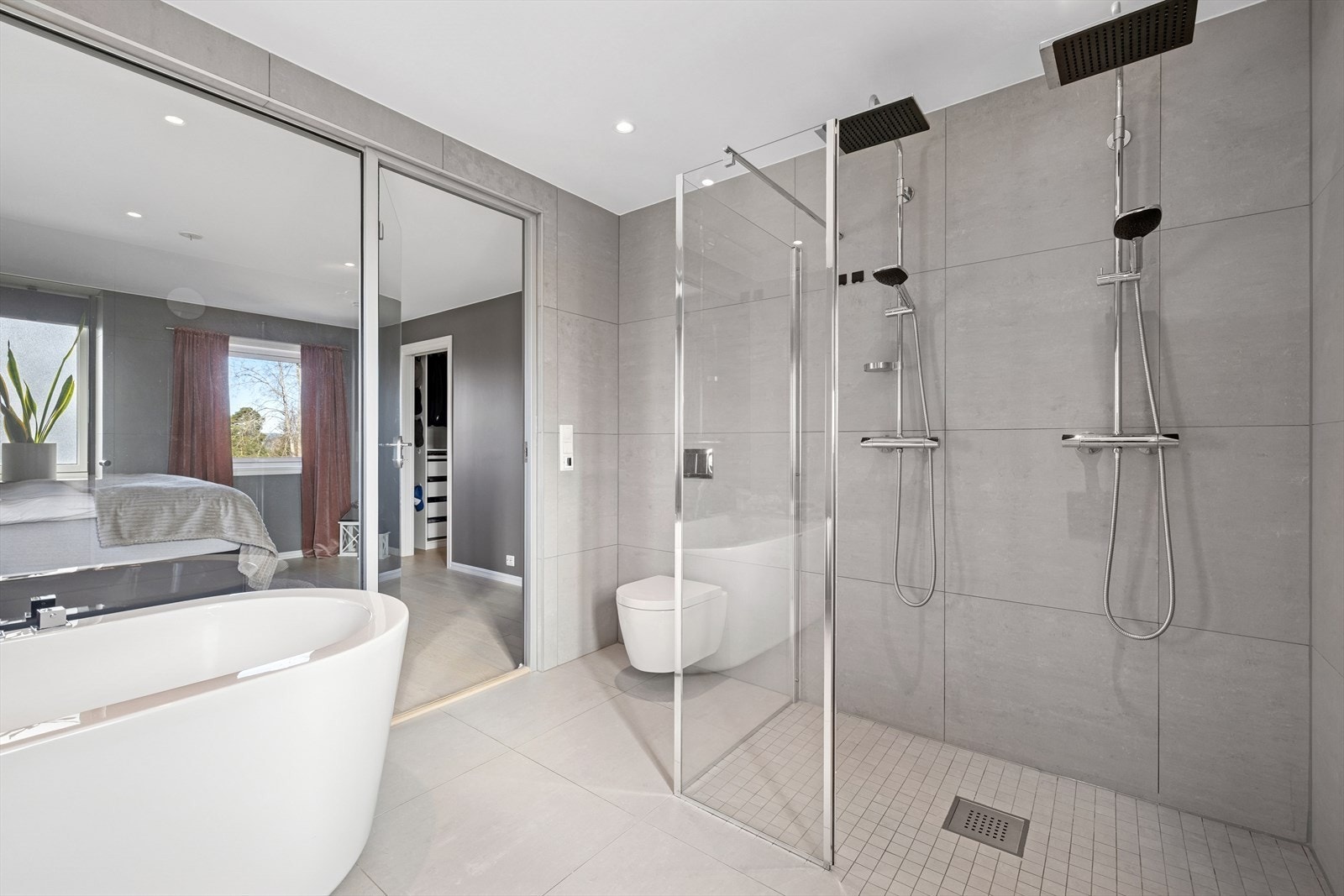 Delikat bad med fliser på vegger og gulv med gulvvarme. Badet har innredning med nedfelt servant, veggmontert toalett, badekar og dusjhjørne med to regnfallsdusjer.. Stort walk-in closet med mye skapplass. Galleribilde