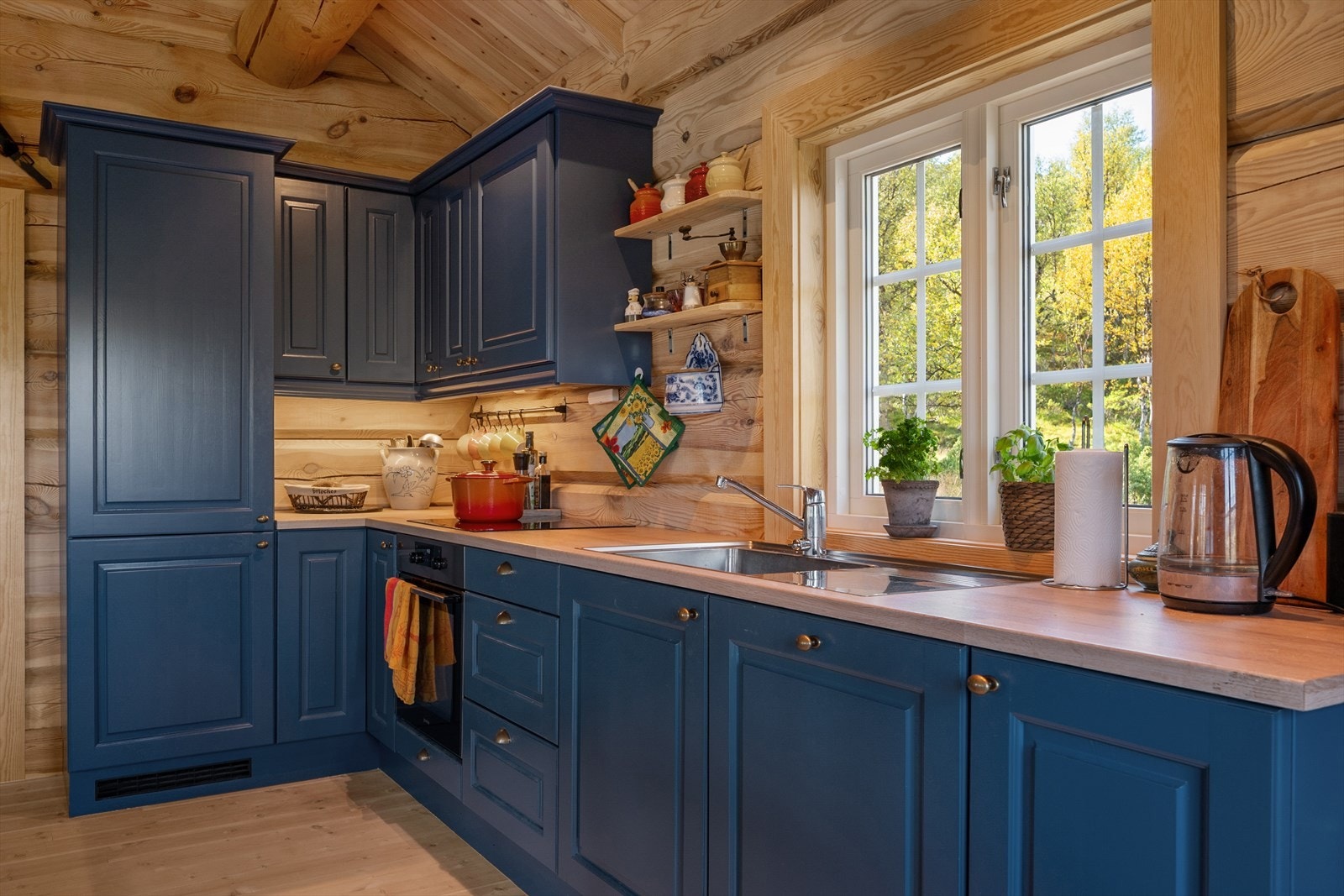 Kjøkkenet har innredning med glatte fronter og er malt i en fin, dyp blåfarge. Det er kjøl/fryseskap, oppvaskmaskin, platetopp, stekeovn og komfyrvakt. Galleribilde