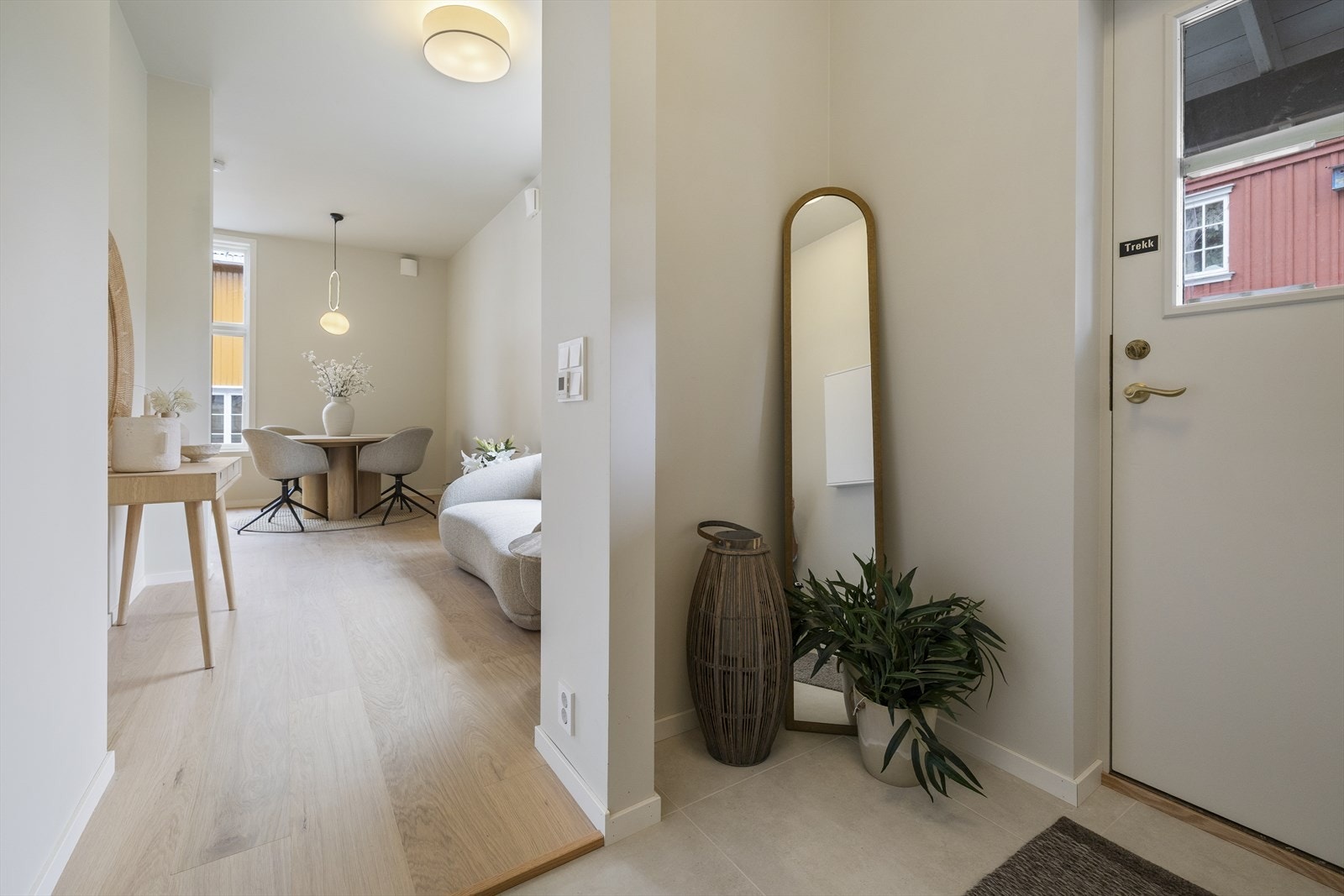 Man ønskes velkommen inn i en lys entré med plass til oppbevaring av sko og yttertøy i nisje. Galleribilde