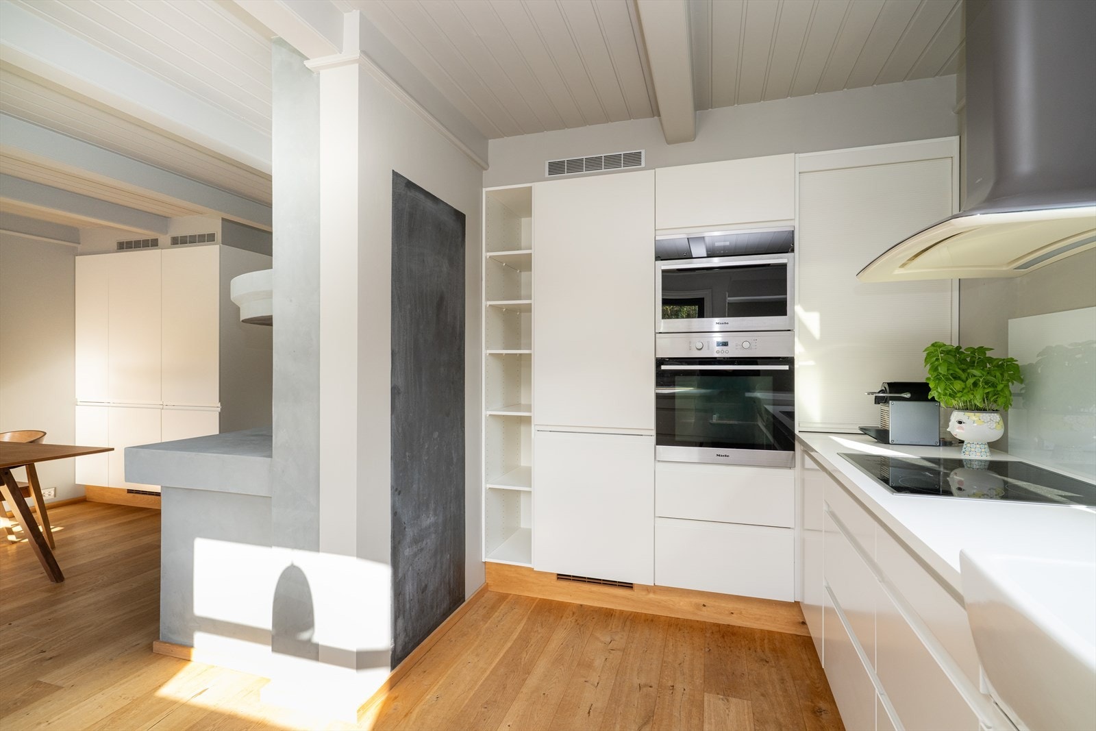 Kjøkkenet har meget godt med oppbevaringsplass i innredning med lakkerte fronter, samt på åpne hyller over benk. Galleribilde