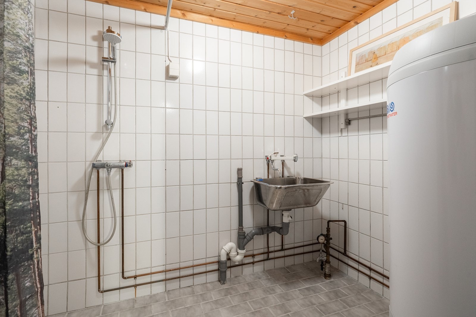 Vaskerommet er helfliset, antatt fra byggeår. Her er det opplegg for og plass til vaskemaskin samt skyllekum i stål. Vaskerommet er også innredet med åpen dusj og varmtvannstank. Galleribilde