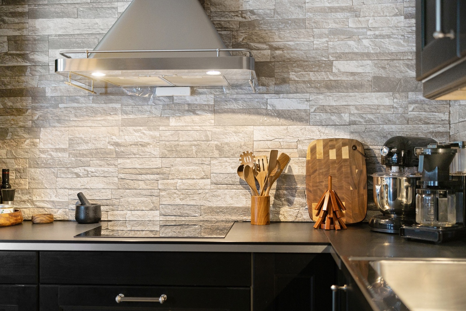 Benkeplater er utført i laminat, og det er valgt en dekorativ og robust stein-/flislagt bakvegg som gir kjøkkenet et eksklusivt og helhetlig uttrykk. Galleribilde