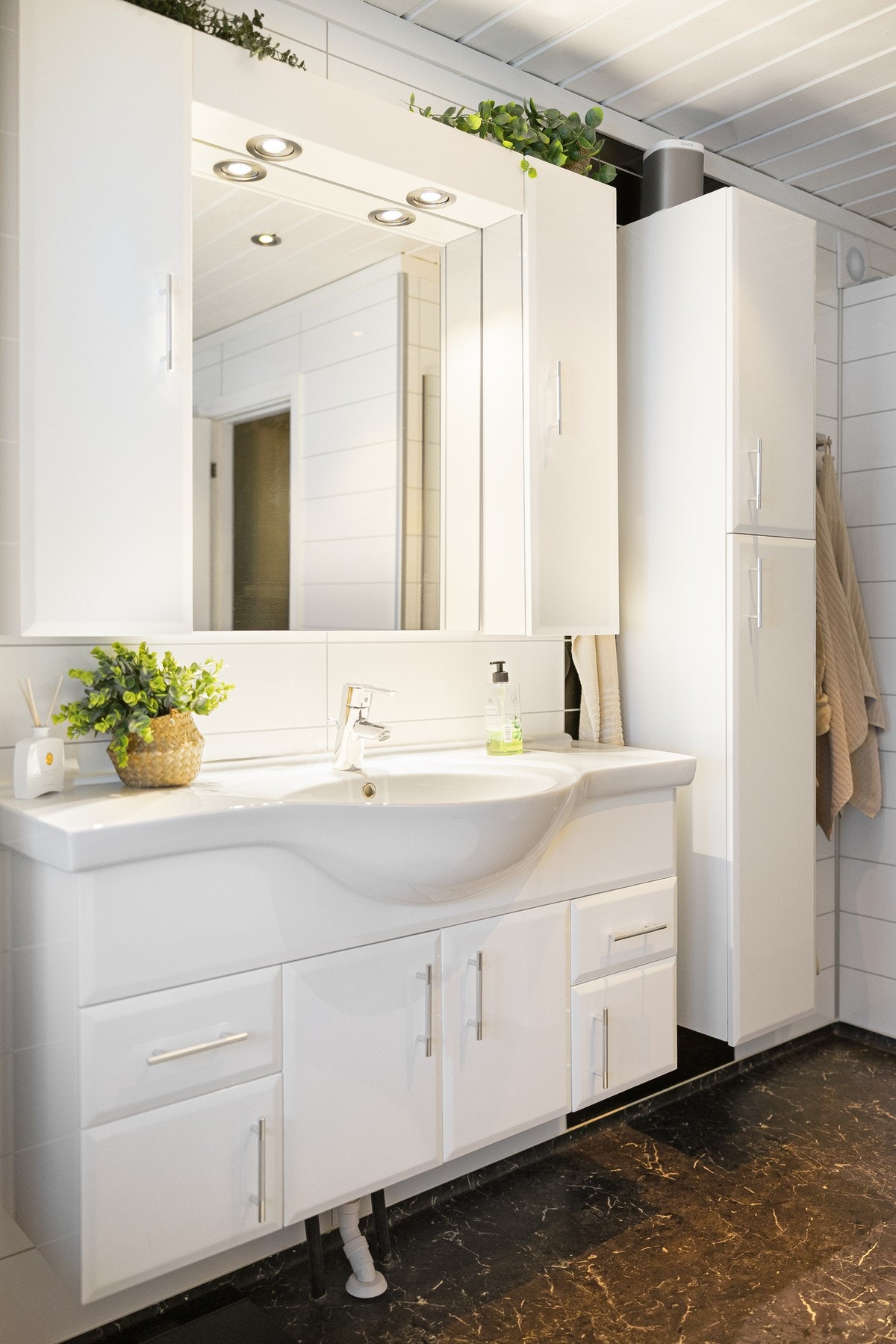 Badet er videre utstyrt med innredning med nedfelt servant og speil, toalett samt dusjnisje med glassdør/hjørneløsning. Veggene er kledd med baderomsplater, mens himlingen har panel. Galleribilde