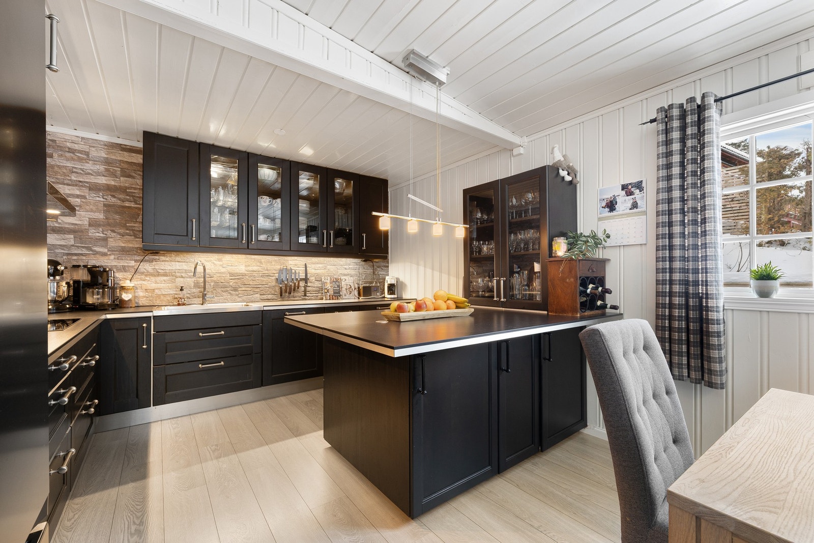 Kjøkkenet fremstår som moderne og funksjonelt, med stilren innredning med glatte, mørke fronter og god skap og benkeplass. Kjøkkenet har en praktisk kjøkkenøy som gir ekstra arbeidsflate og naturlig samlingspunkt, samt gode oppbevaringsløsninger i både un Galleribilde