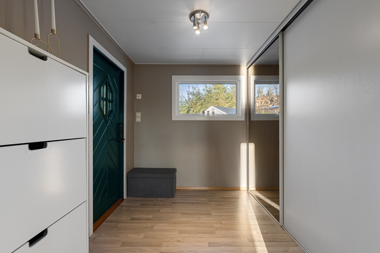 Romslig entré med bred skyvedørsgarderobe er praktisk når familien skal inn/ut samtidig. Elektronisk kodelås er montert på inngangsdøren. I gulvet er det varmekabler. Galleribilde