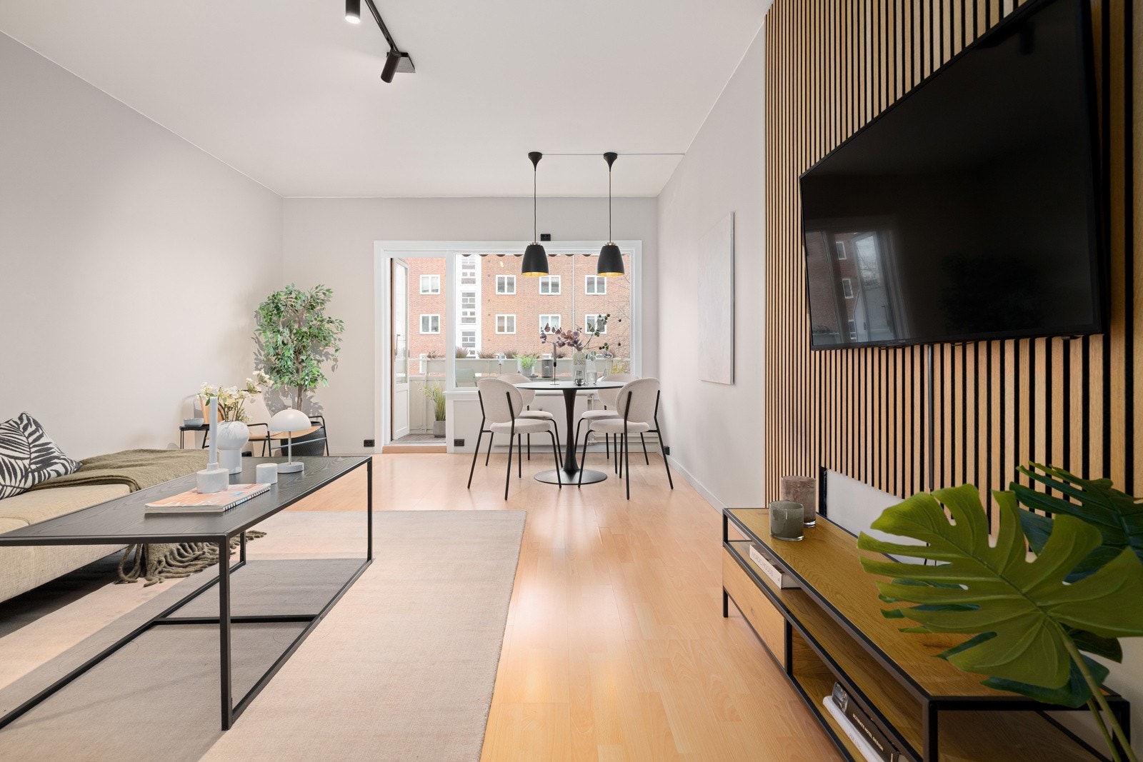 God standard med laminat på gulv og glatte lysmalte overflater kombinert med stilige trespiler ved tv-en. Galleribilde