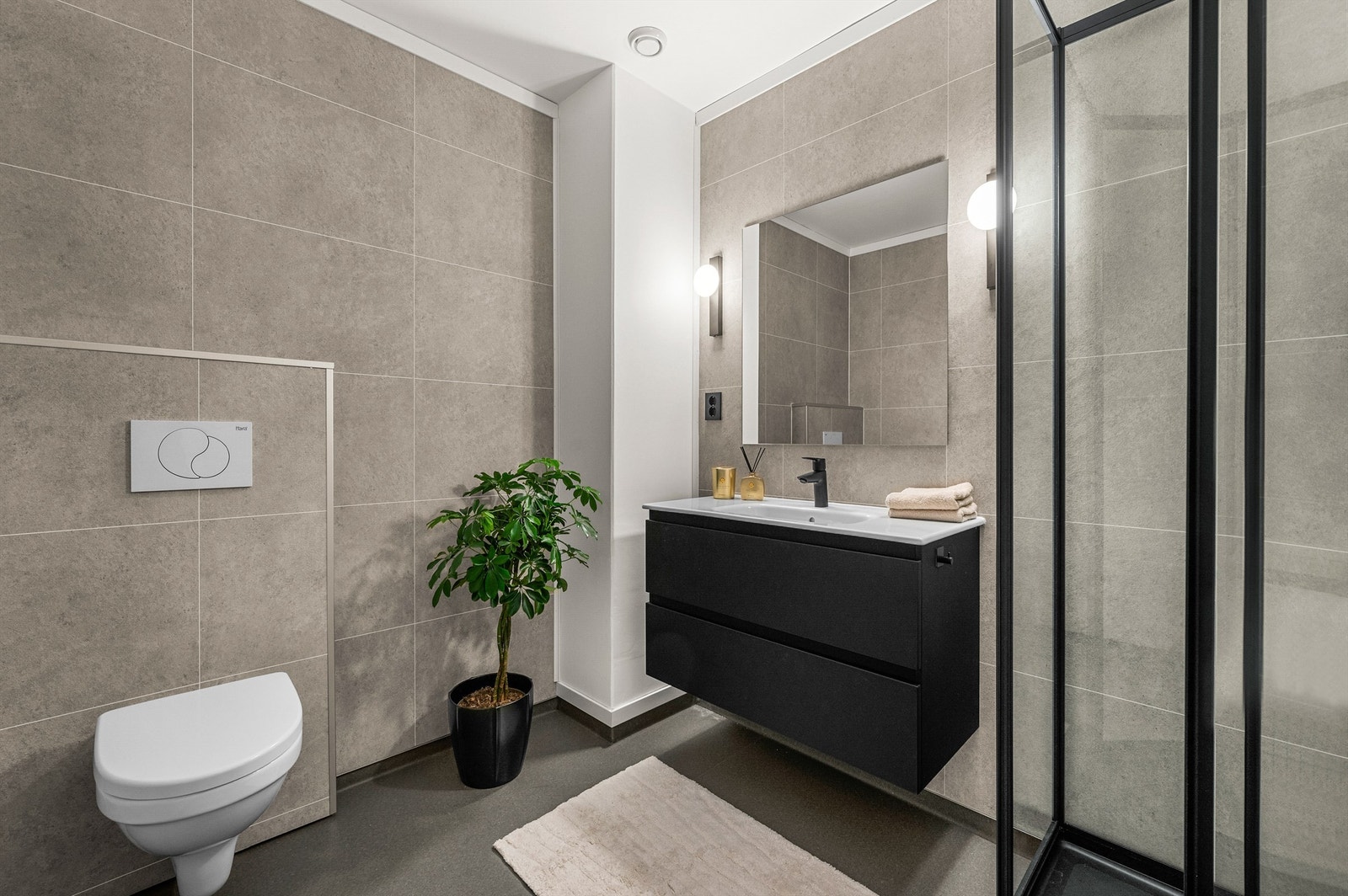 Pent bad på 5,1 kvm innredet med servantskap med speil og lys, vegghengt toalett og dusjhjørne. Badet ble oppgradert i 2026. Galleribilde