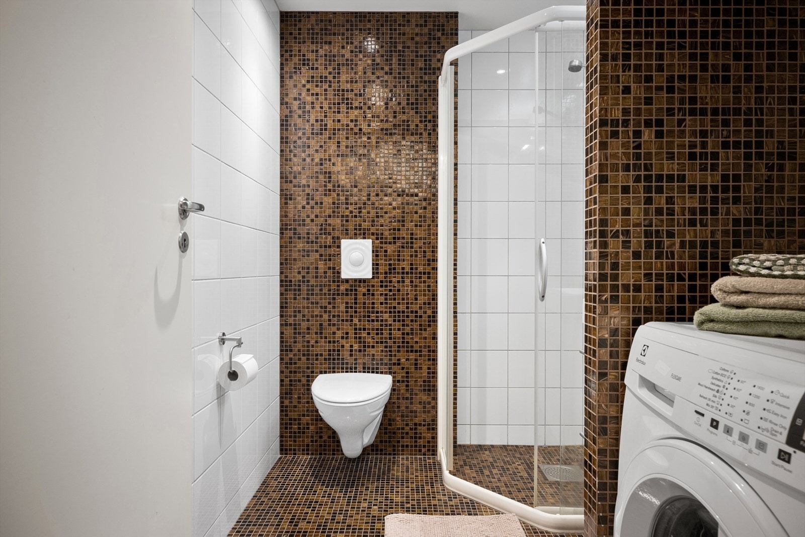 Det er innredet med en hvit servant seksjon med skuffer og integrert speil med belysning, et dusjkabinett og vegghengt toalett. Galleribilde