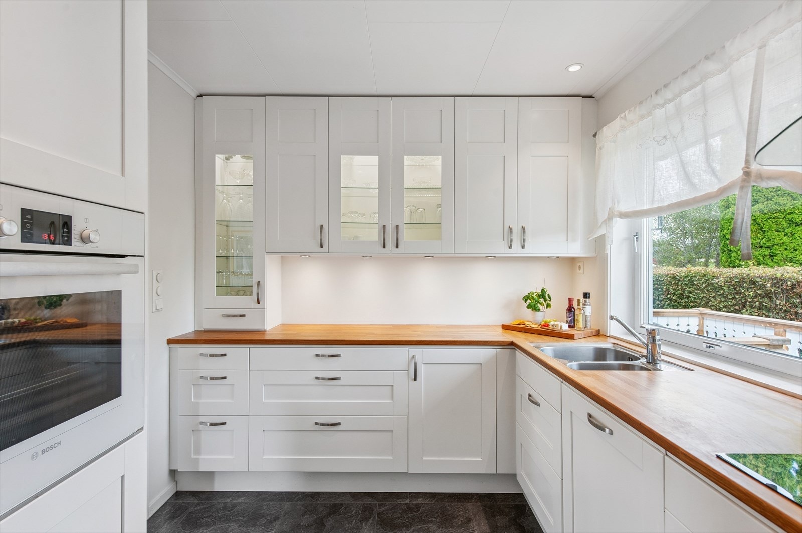 Kjøkkenet har en praktisk L-form med rikelig skap- og benkeplass. Galleribilde